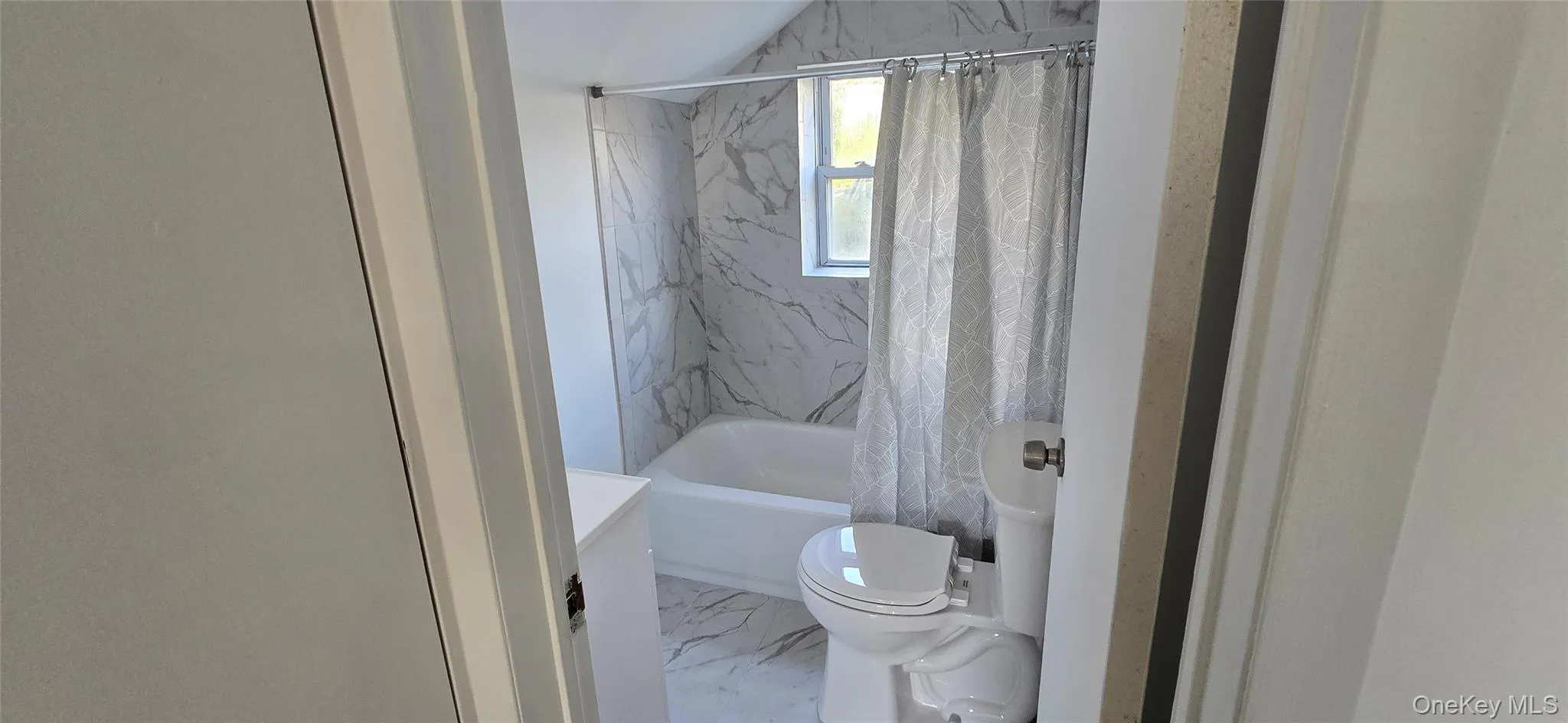 Full bath with shower / bath combination with curtain and marble look tiles Full bath with shower / bath combination with curtain and marble look tiles
