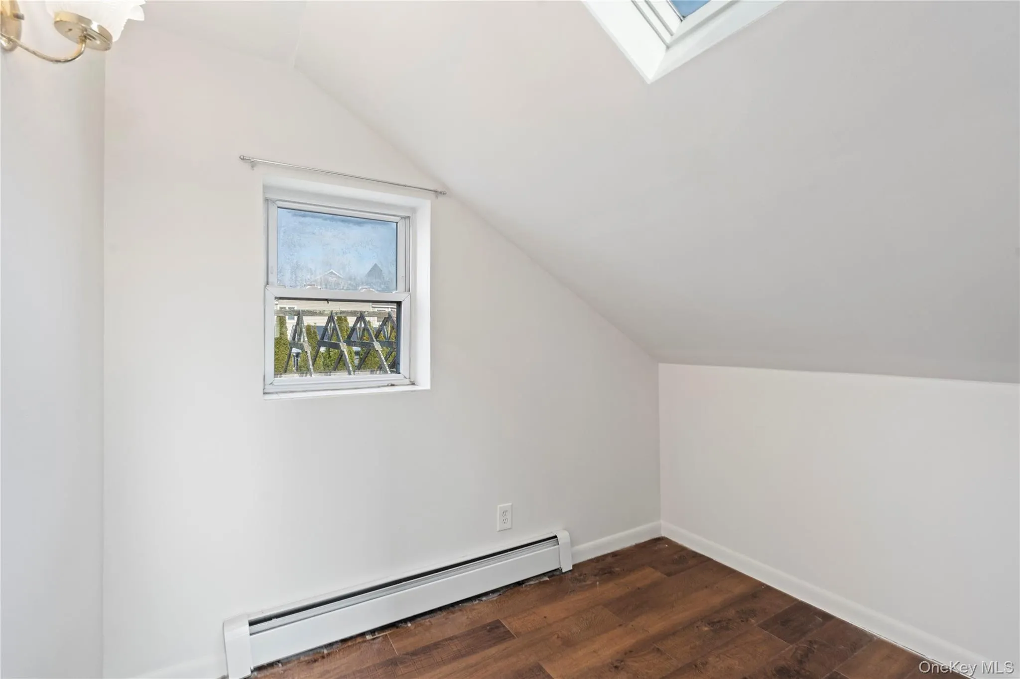 Bonus room with baseboard heating, vaulted ceiling, a skylight, and dark wood-type flooring Bonus room with baseboard heating, vaulted ceiling, a skylight, and dark wood-type flooring