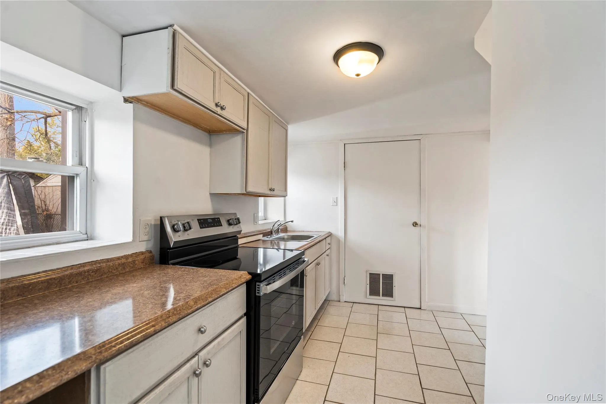 Kitchen featuring electric range, light tile patterned floors, and vaulted ceiling Kitchen featuring electric range, light tile patterned floors, and vaulted ceiling
