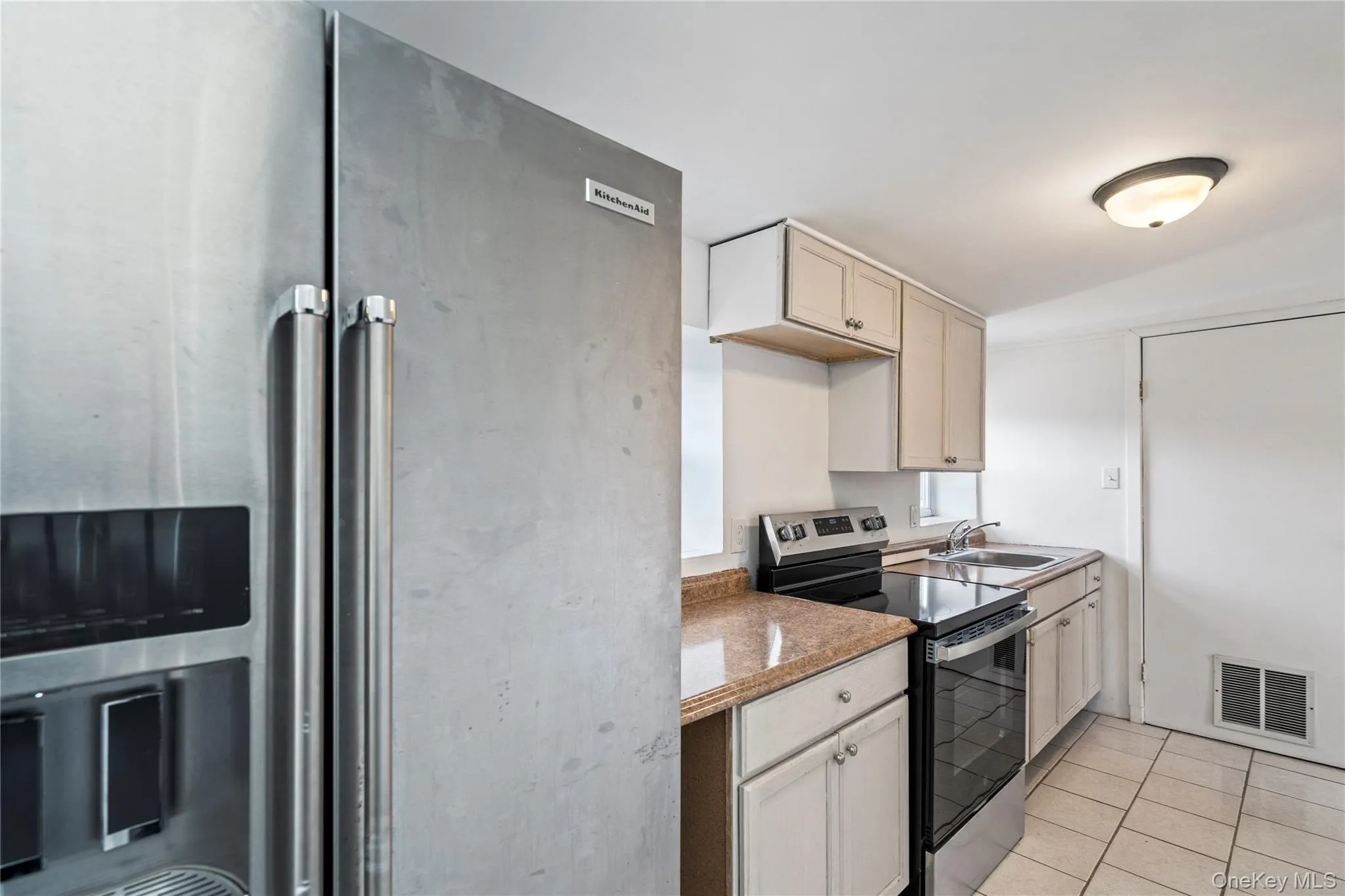 Kitchen with stainless steel appliances, light tile patterned floors, and light stone counters Kitchen with stainless steel appliances, light tile patterned floors, and light stone counters