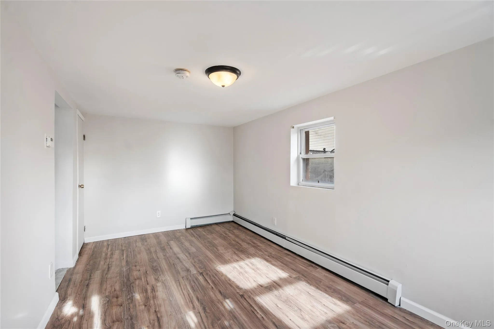 Spare room featuring wood finished floors and a baseboard radiator Spare room featuring wood finished floors and a baseboard radiator