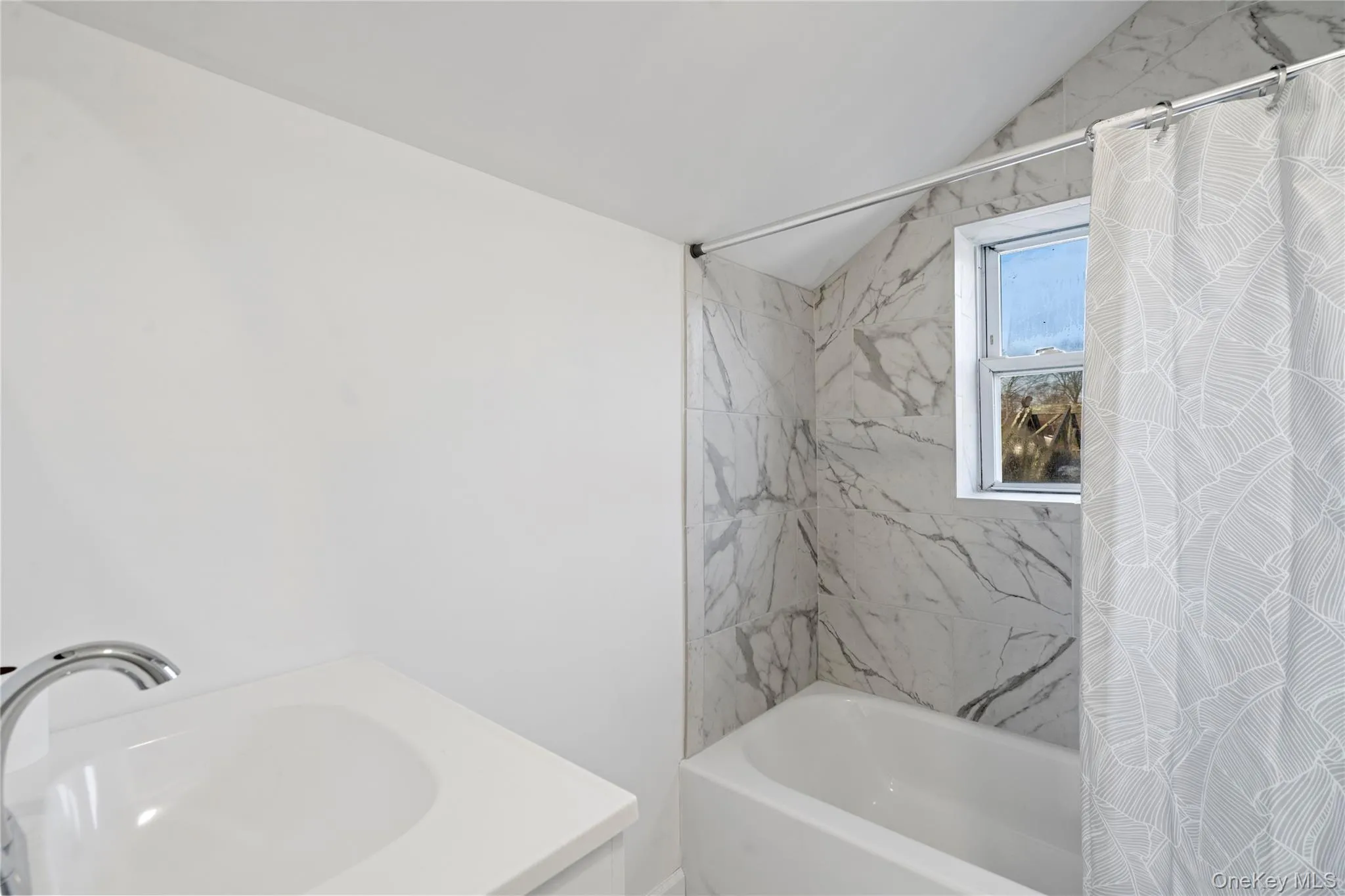 Full bath featuring vanity, shower / tub combo, and vaulted ceiling Full bath featuring vanity, shower / tub combo, and vaulted ceiling