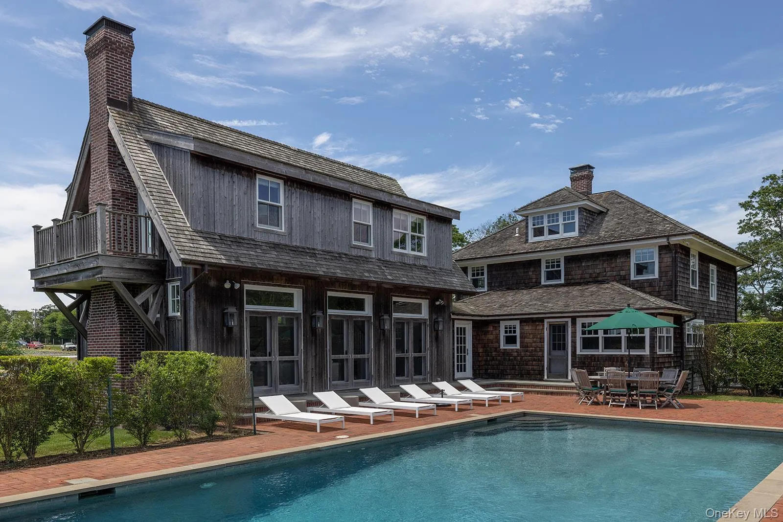Back of house featuring a chimney, an outdoor pool, a patio area, and outdoor dining space Back of house featuring a chimney, an outdoor pool, a patio area, and outdoor dining space