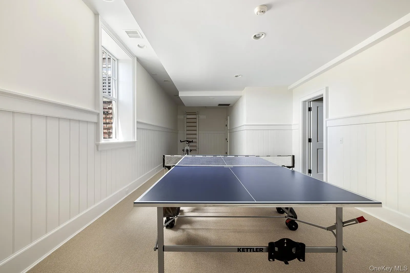 Recreation room featuring carpet flooring, recessed lighting, and a wainscoted wall Recreation room featuring carpet flooring, recessed lighting, and a wainscoted wall