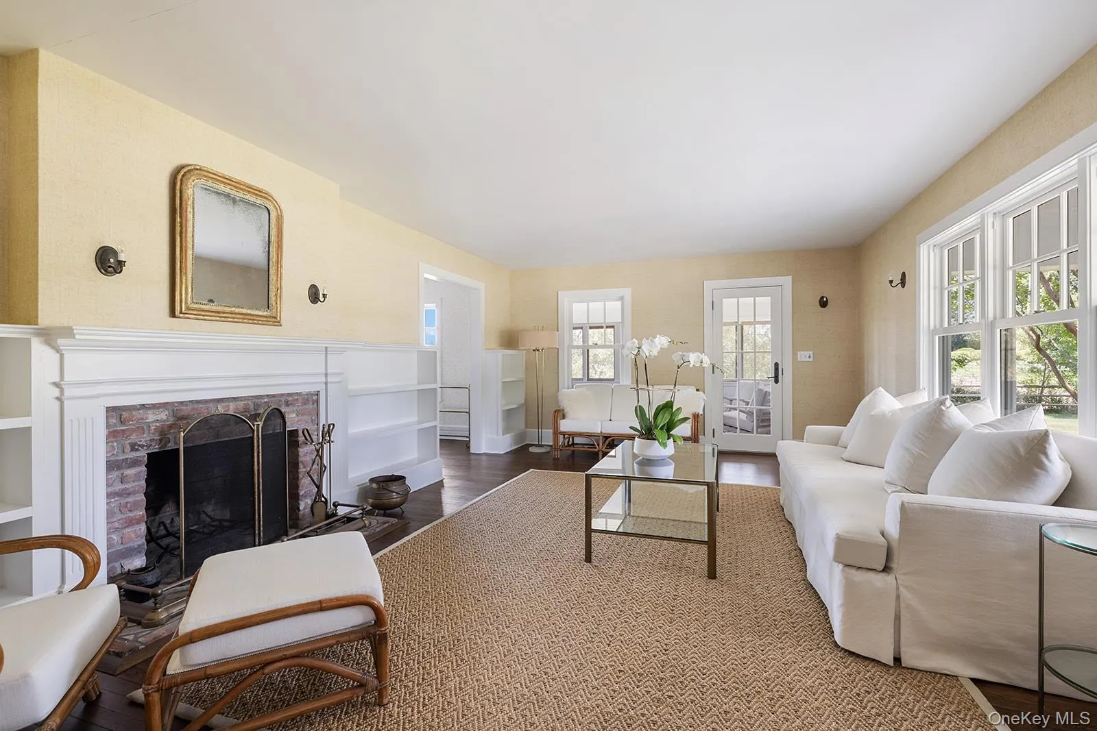 Living room featuring wood finished floors, a brick fireplace, and healthy amount of natural light Living room featuring wood finished floors, a brick fireplace, and healthy amount of natural light