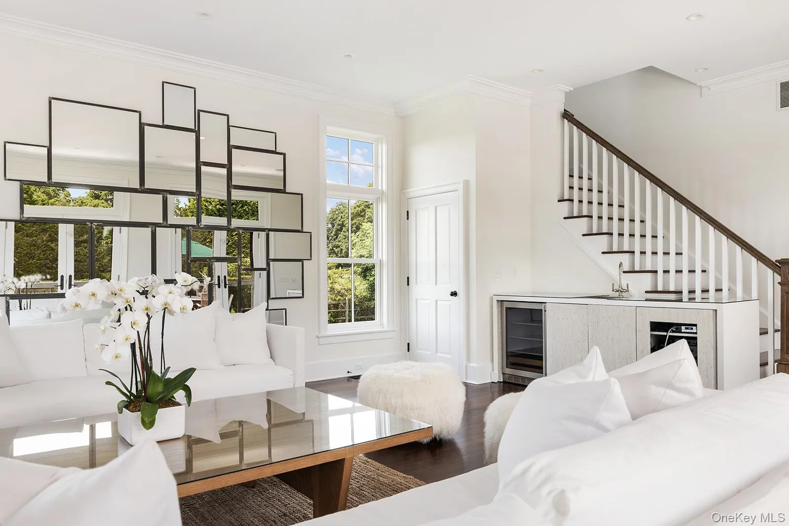 Living room with dark wood finished floors, wine cooler, stairs, and crown molding Living room with dark wood finished floors, wine cooler, stairs, and crown molding