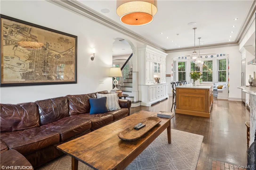 Living room with ornamental molding, a notable chandelier, decorative columns, and dark wood-type flooring Living room with ornamental molding, a notable chandelier, decorative columns, and dark wood-type flooring