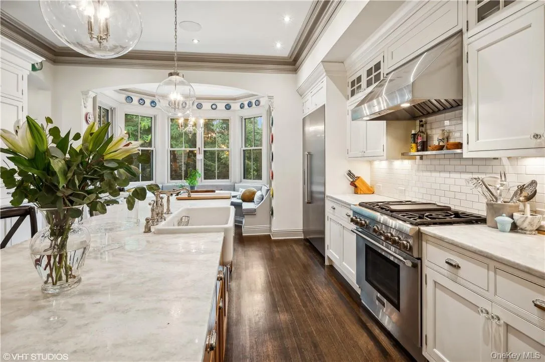 Kitchen with wall chimney range hood, pendant lighting, dark hardwood / wood-style floors, high end appliances, and backsplash Kitchen with wall chimney range hood, pendant lighting, dark hardwood / wood-style floors, high end appliances, and backsplash
