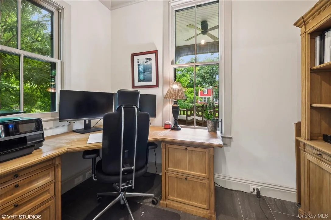 Office space featuring dark hardwood / wood-style flooring, ceiling fan, built in desk, and a healthy amount of sunlight Office space featuring dark hardwood / wood-style flooring, ceiling fan, built in desk, and a healthy amount of sunlight