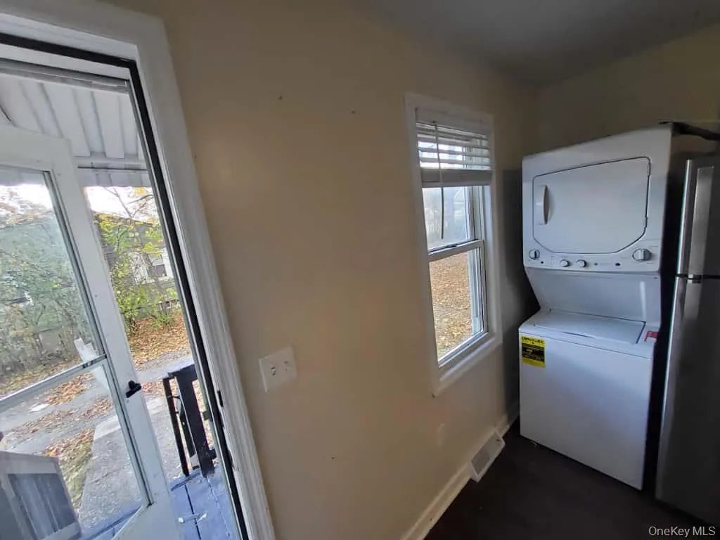 Laundry room with stacked washer and clothes dryer and baseboards Laundry room with stacked washer and clothes dryer and baseboards