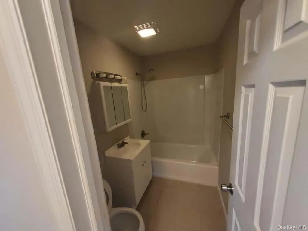 Full bath with vanity, light tile patterned floors, and bathing tub / shower combination Full bath with vanity, light tile patterned floors, and bathing tub / shower combination