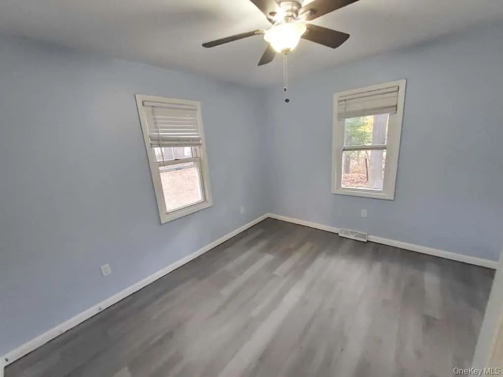 Unfurnished room with wood finished floors and a ceiling fan Unfurnished room with wood finished floors and a ceiling fan