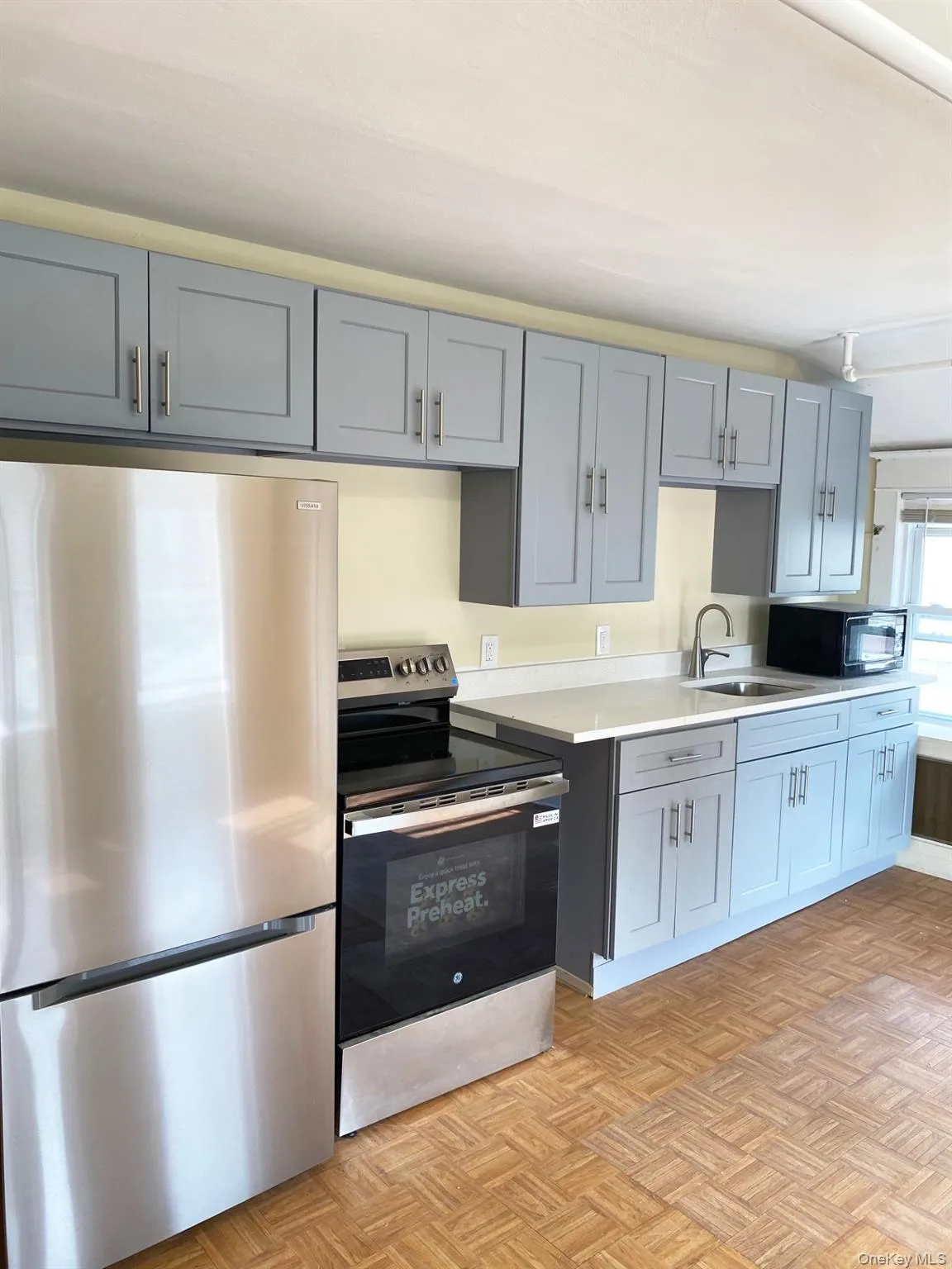 Kitchen with appliances with stainless steel finishes and gray cabinetry Kitchen with appliances with stainless steel finishes and gray cabinetry