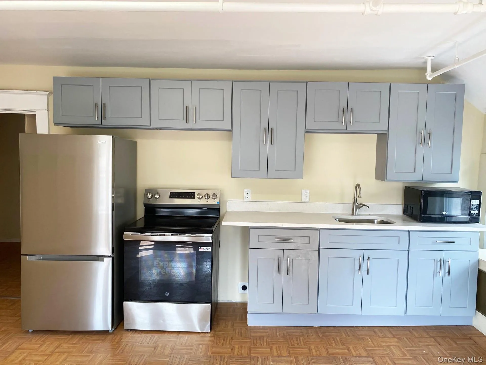 Kitchen with stainless steel appliances, gray cabinetry, and light stone countertops Kitchen with stainless steel appliances, gray cabinetry, and light stone countertops