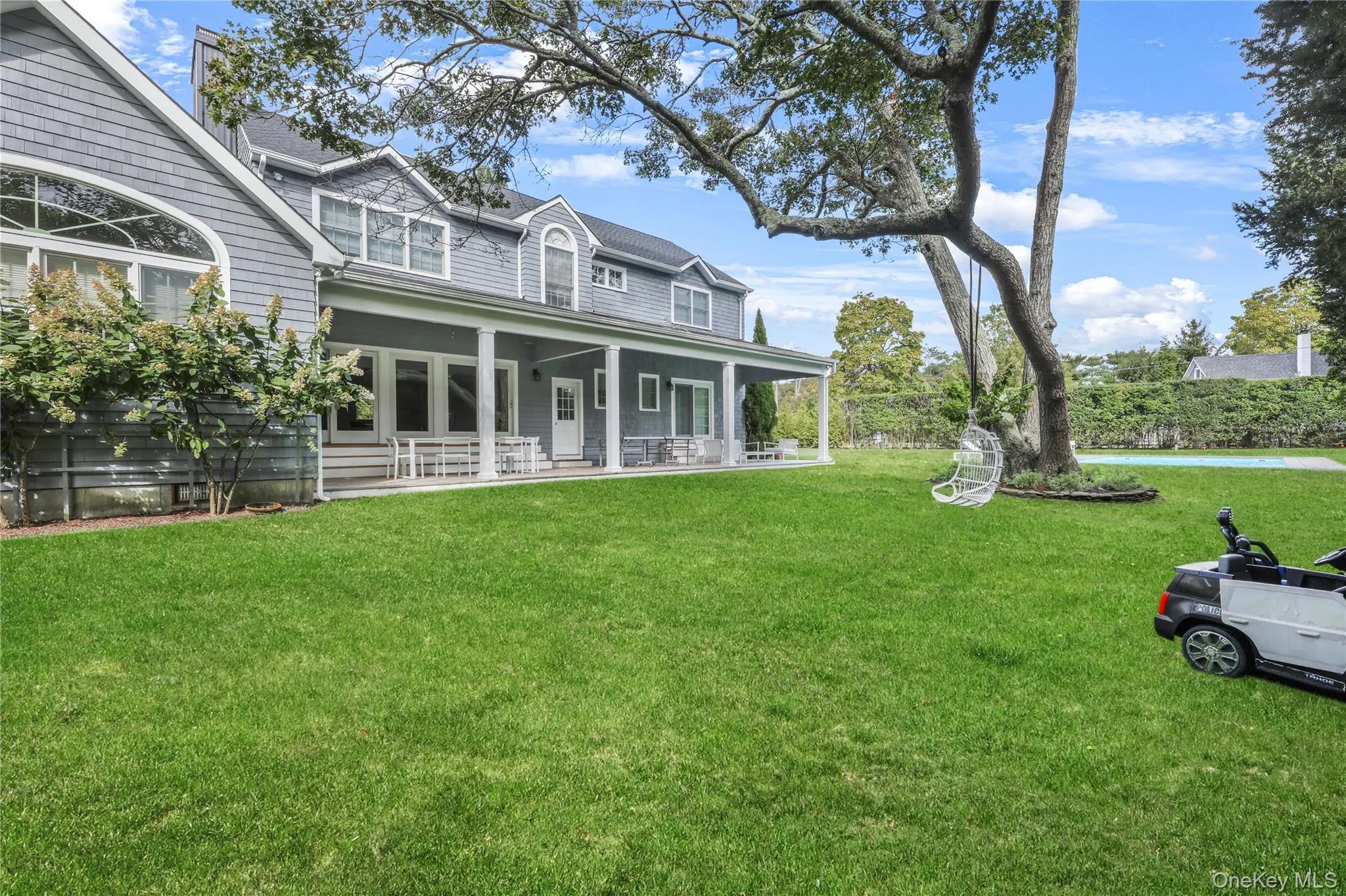 Rear view of property featuring a lawn, covered porch, a chimney, and roof with shingles Rear view of property featuring a lawn, covered porch, a chimney, and roof with shingles