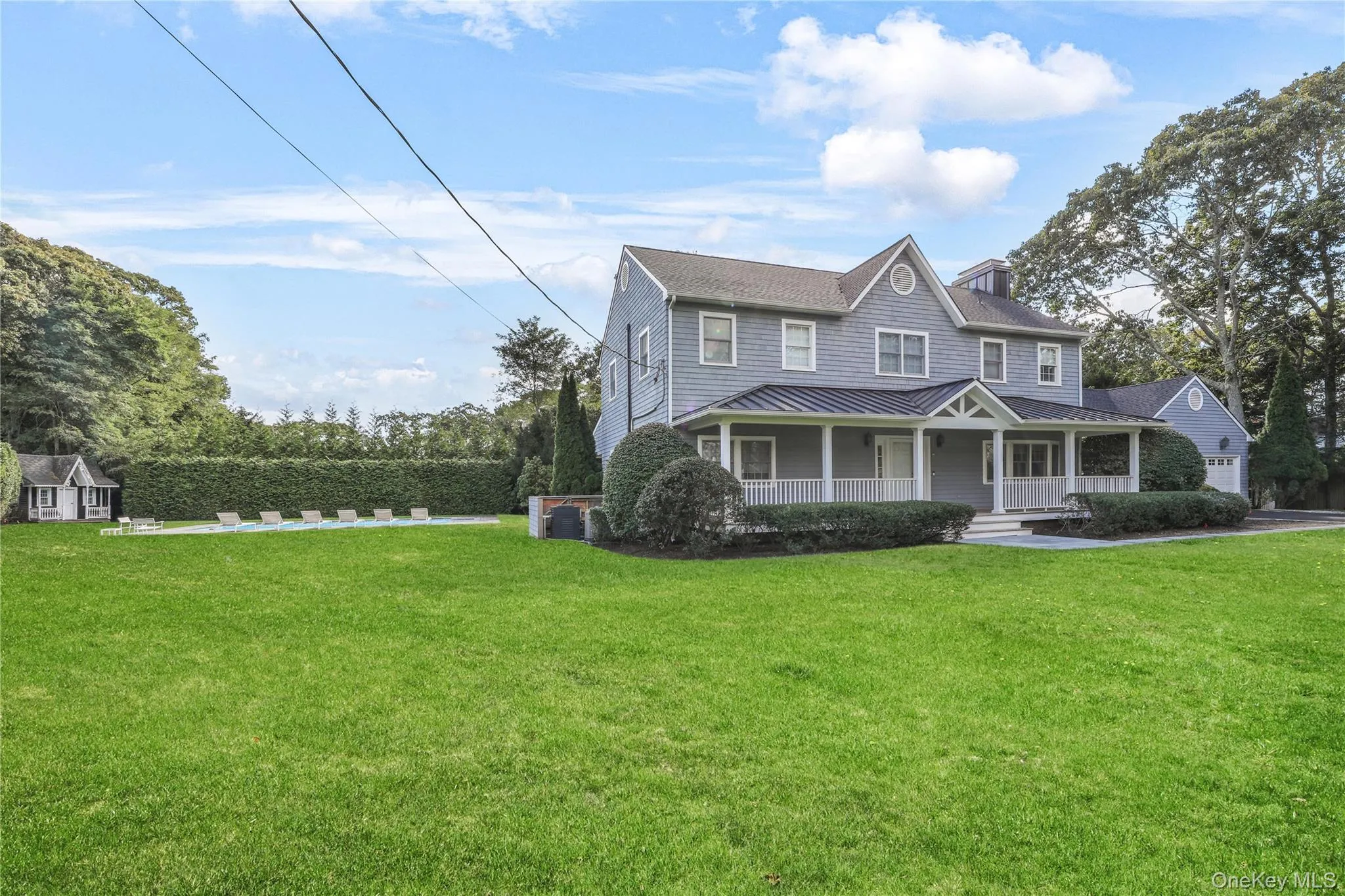 Colonial house with a porch, a front yard, a standing seam roof, and a metal roof Colonial house with a porch, a front yard, a standing seam roof, and a metal roof