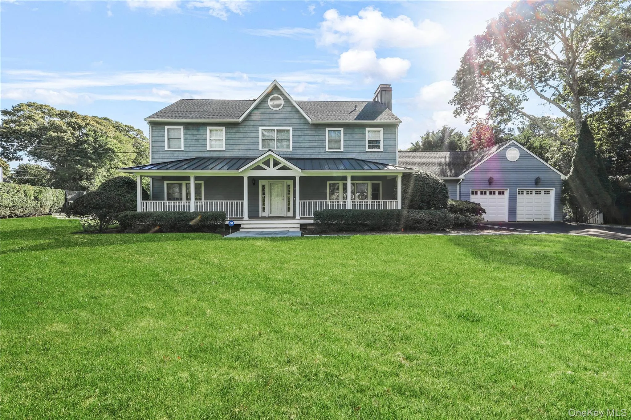 View of front of home featuring a porch, a standing seam roof, a front yard, and a garage View of front of home featuring a porch, a standing seam roof, a front yard, and a garage
