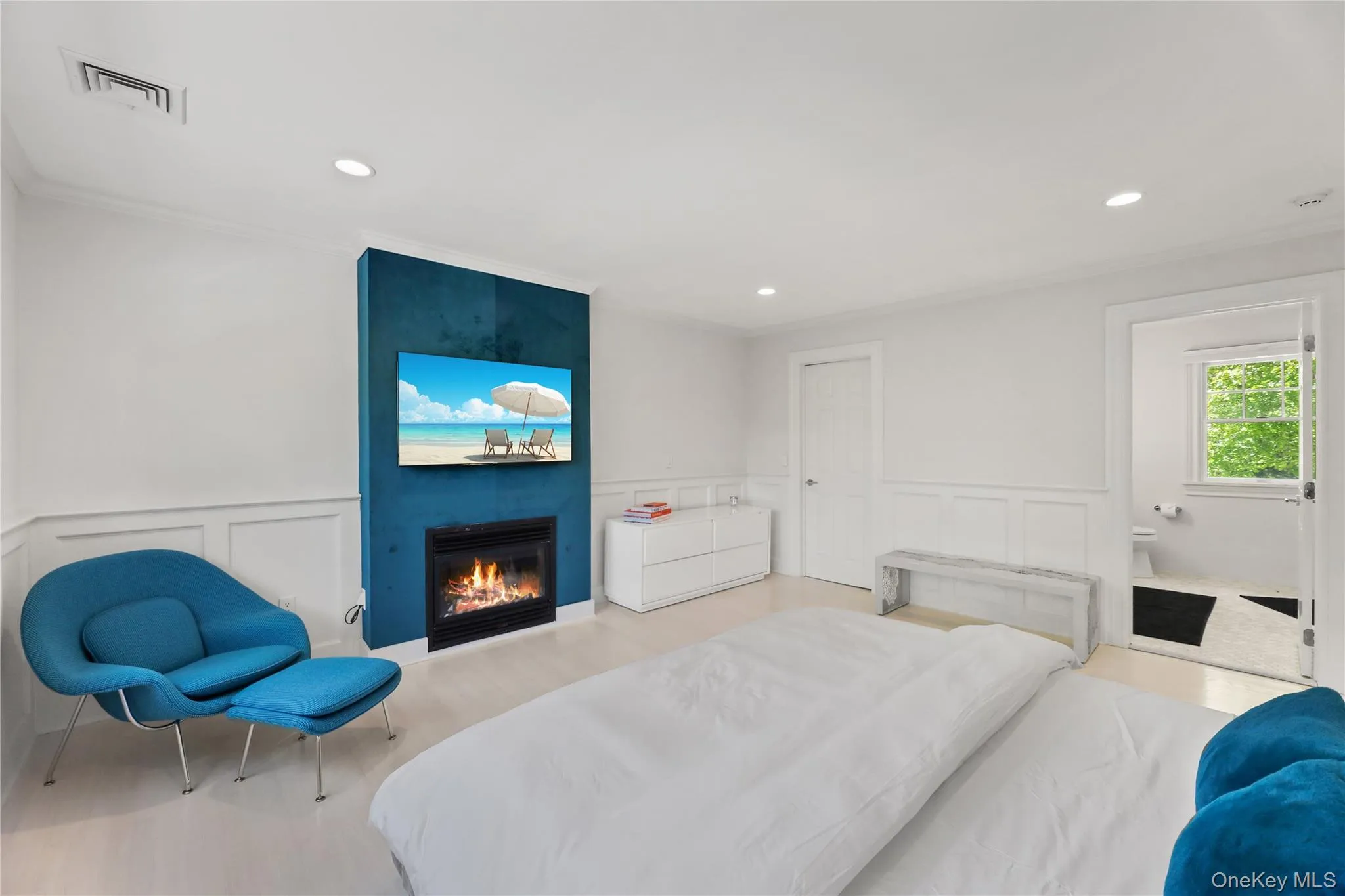 Bedroom featuring a decorative wall, a fireplace, wainscoting, and visible vents Bedroom featuring a decorative wall, a fireplace, wainscoting, and visible vents
