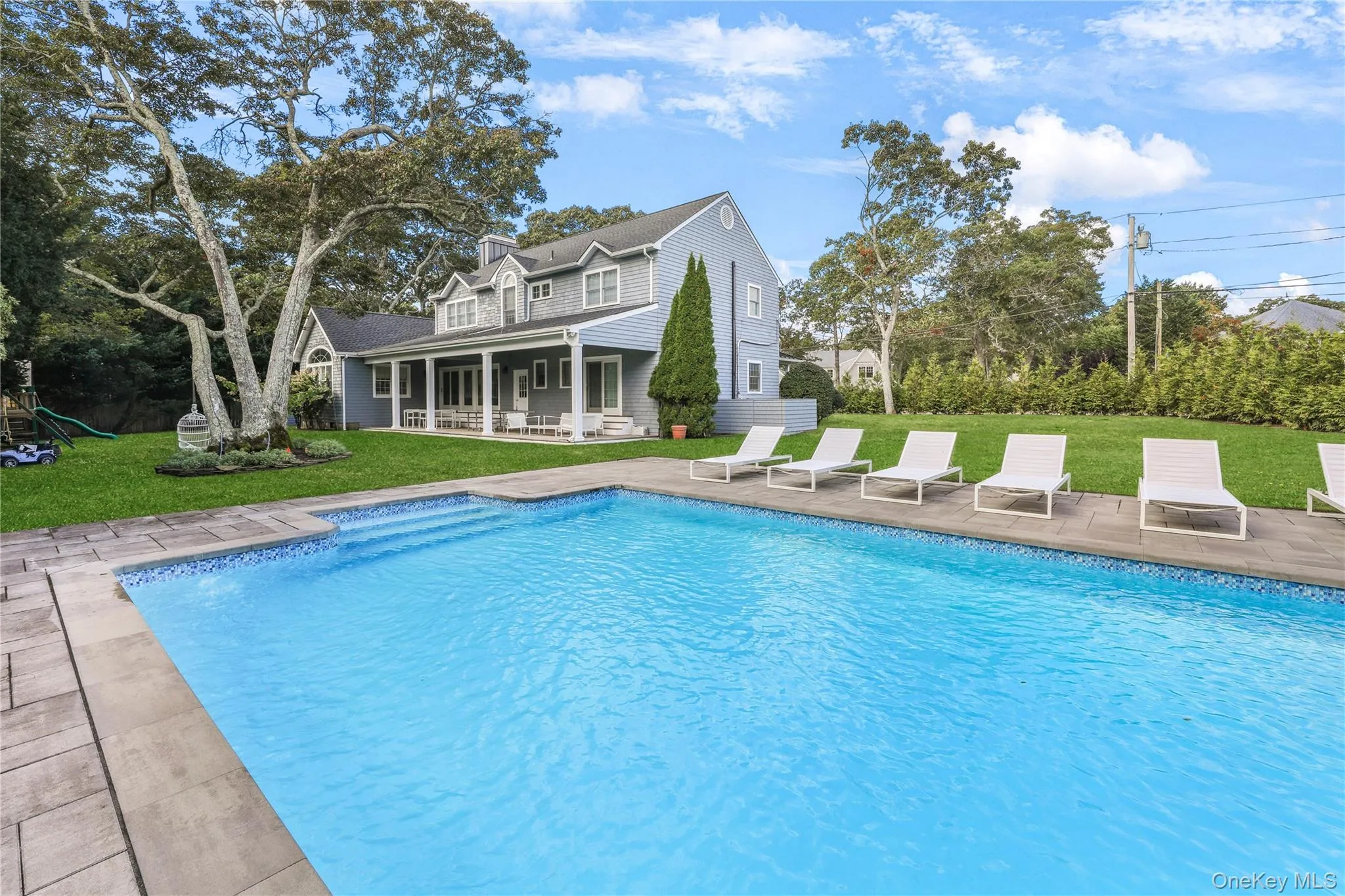Outdoor pool with a lawn, a patio area, a porch, and a playground Outdoor pool with a lawn, a patio area, a porch, and a playground