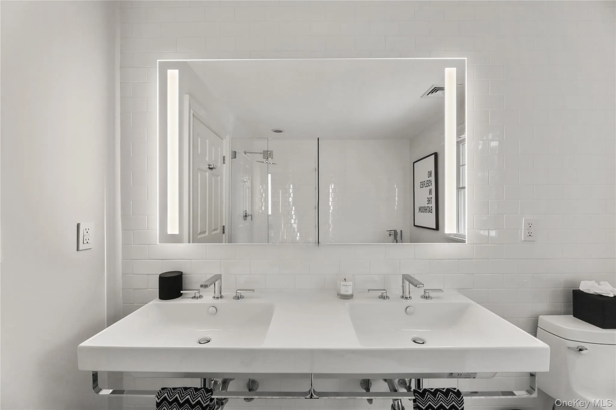 Bathroom featuring toilet, double sink, backsplash, and tile walls Bathroom featuring toilet, double sink, backsplash, and tile walls