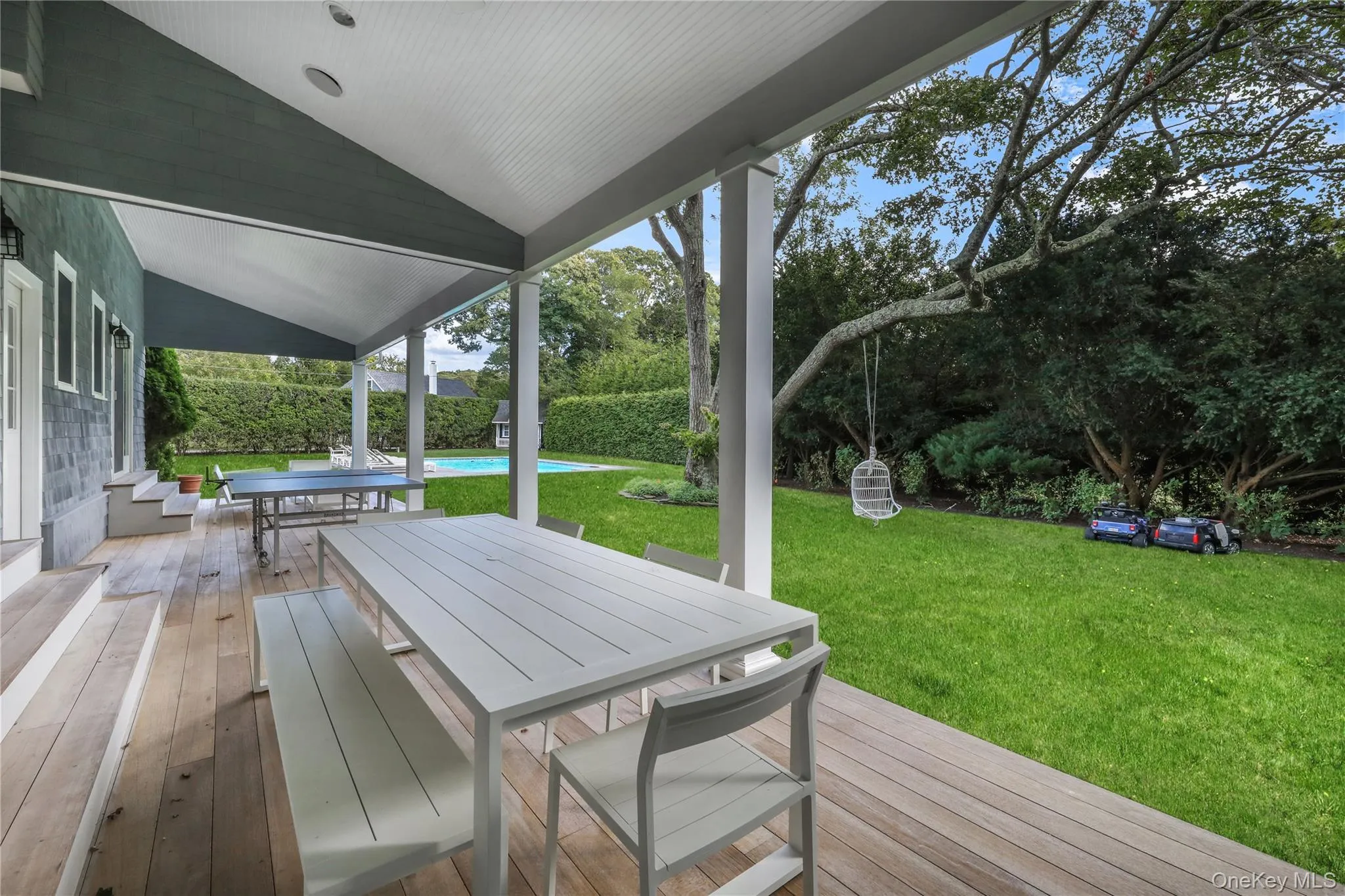 Deck featuring outdoor dining space, a yard, an outdoor pool, and view of wooded area Deck featuring outdoor dining space, a yard, an outdoor pool, and view of wooded area