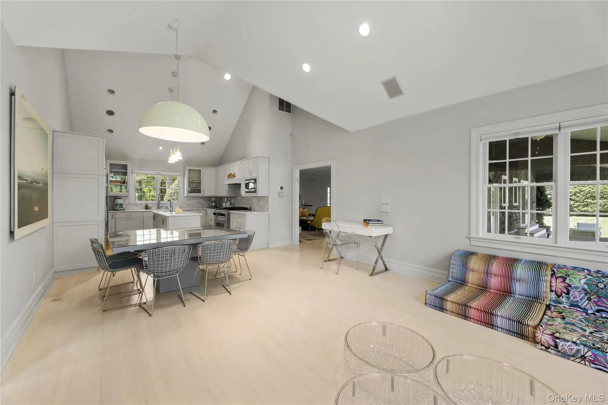 Dining area with light wood-type flooring, high vaulted ceiling, baseboards, and visible vents Dining area with light wood-type flooring, high vaulted ceiling, baseboards, and visible vents