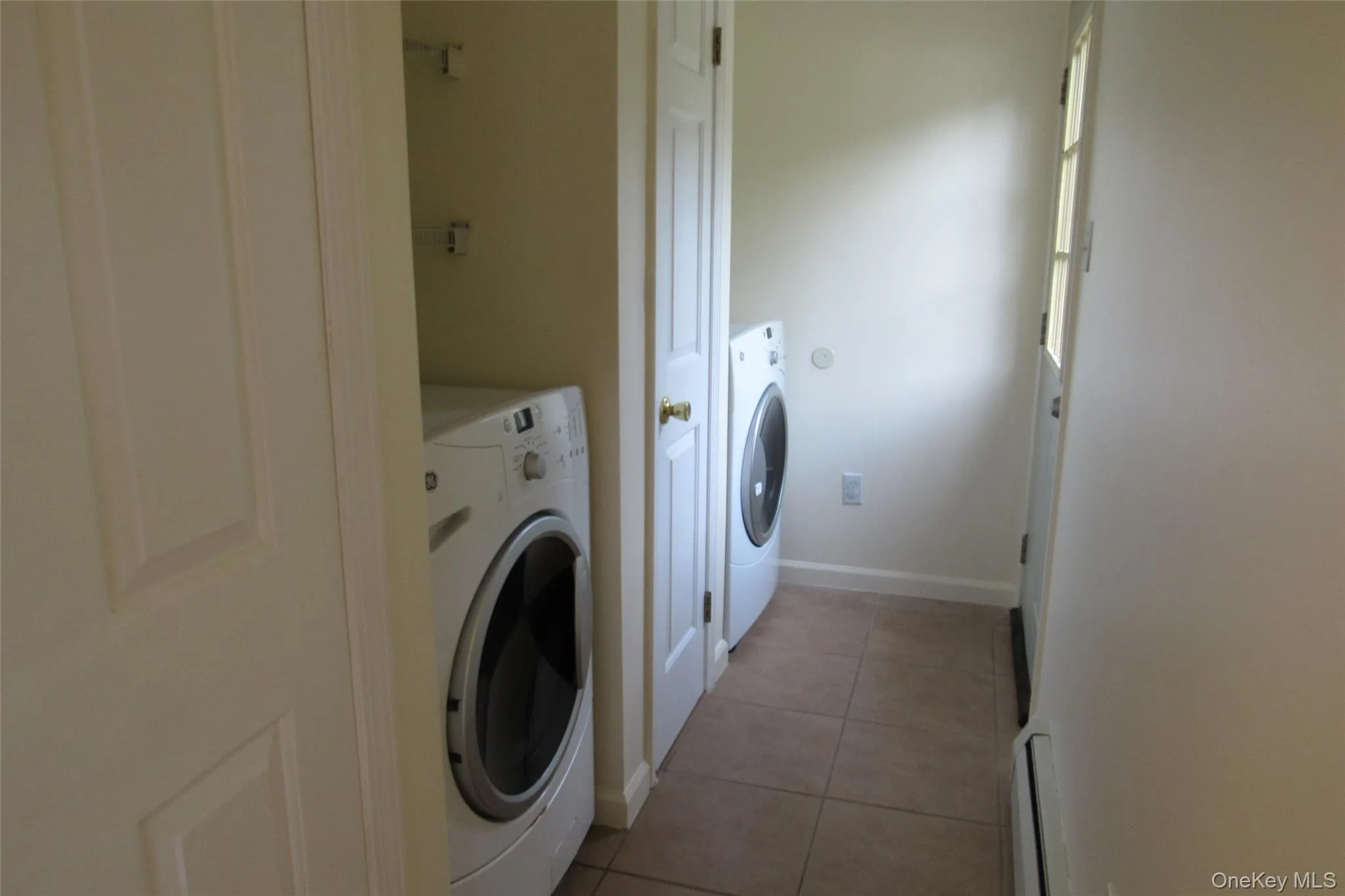Laundry room with light tile patterned floors, baseboard heating, and washer and dryer Laundry room with light tile patterned floors, baseboard heating, and washer and dryer