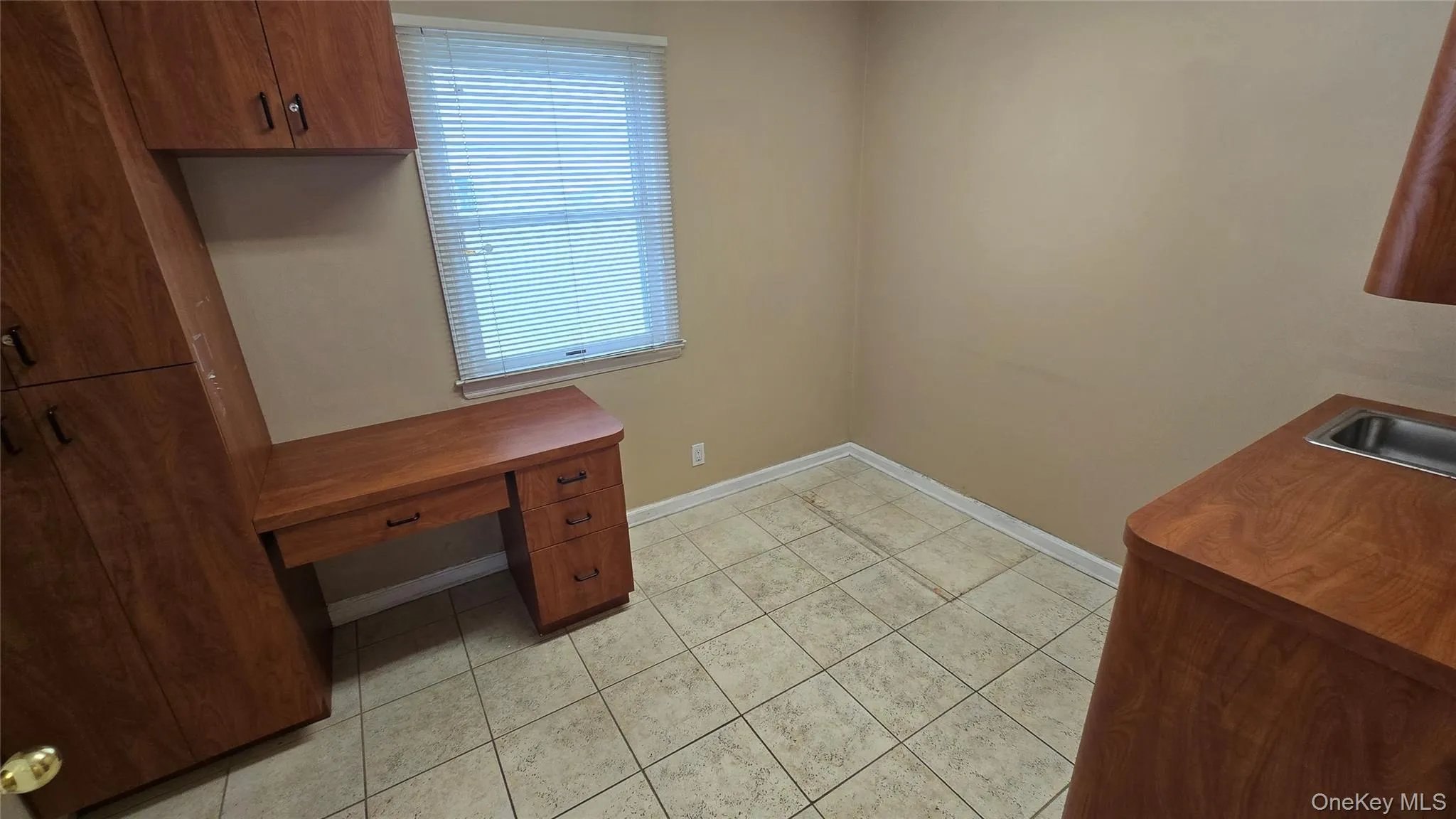 Unfurnished office featuring light tile patterned floors and baseboards Unfurnished office featuring light tile patterned floors and baseboards