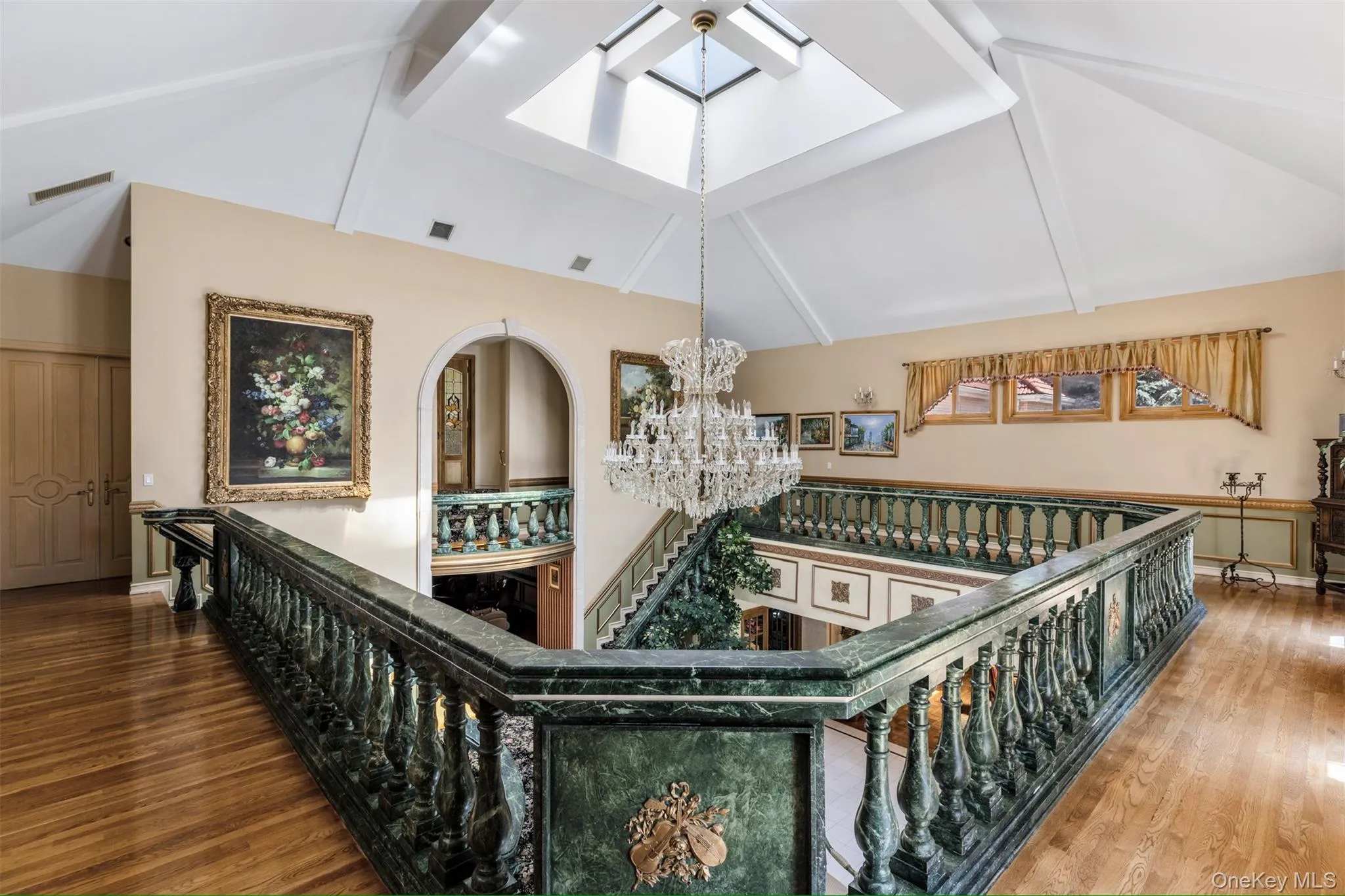 Stairway with a chandelier, wood finished floors, high vaulted ceiling, beamed ceiling, and a skylight Stairway with a chandelier, wood finished floors, high vaulted ceiling, beamed ceiling, and a skylight