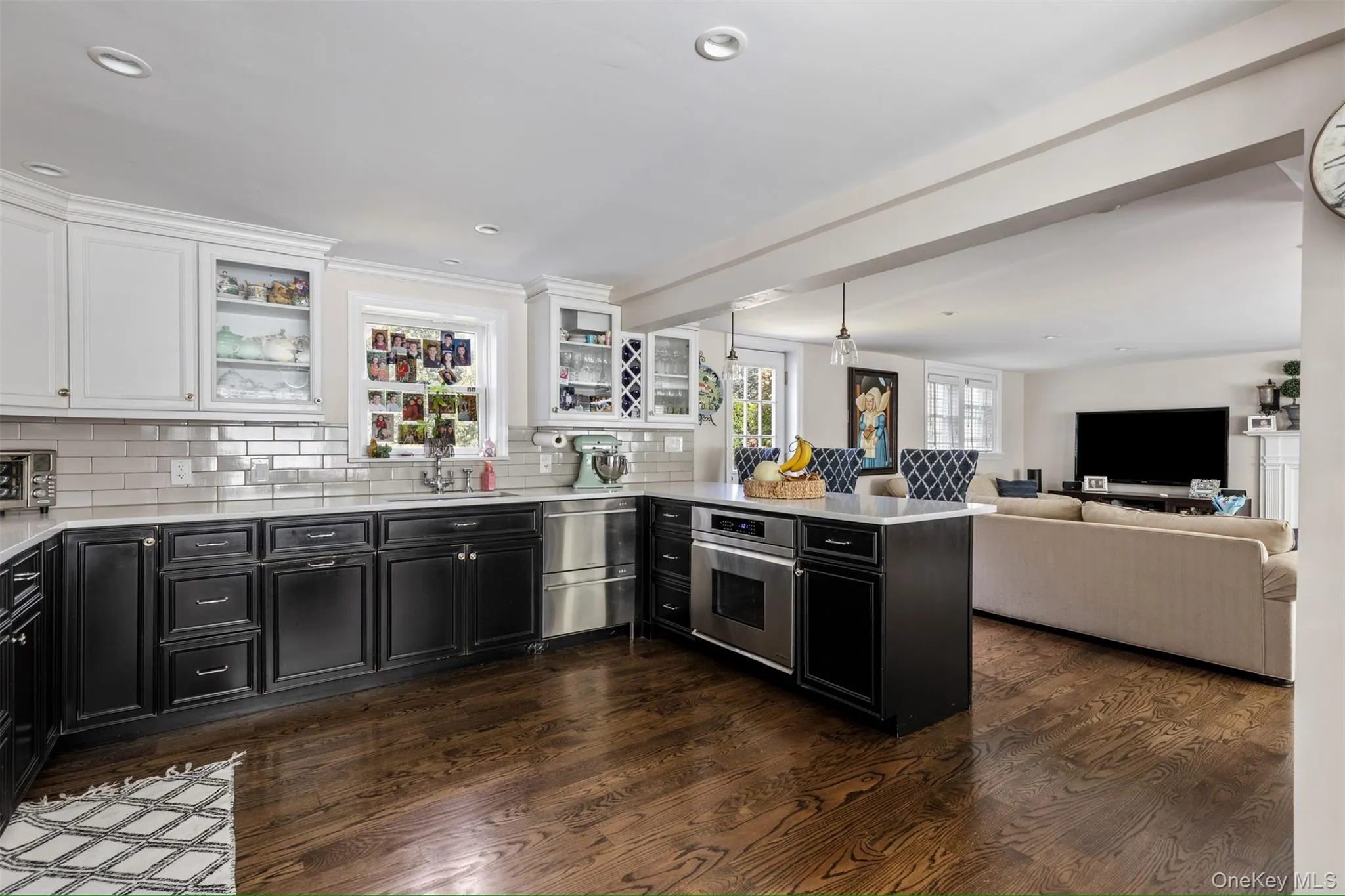Kitchen with dark cabinetry, a peninsula, white cabinets, light stone countertops, and recessed lighting Kitchen with dark cabinetry, a peninsula, white cabinets, light stone countertops, and recessed lighting