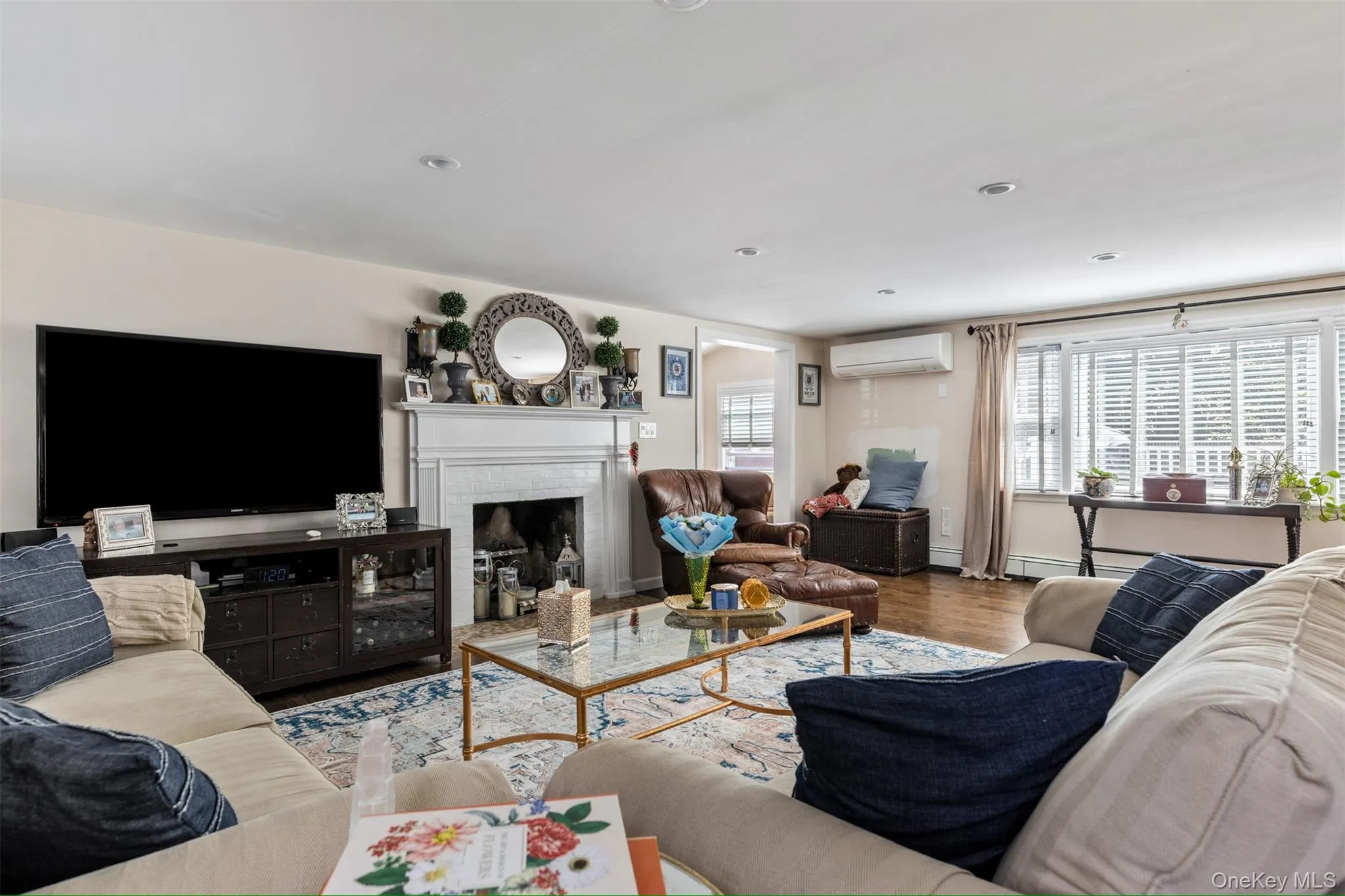 Living room featuring a fireplace, wood finished floors, a wall mounted air conditioner, and recessed lighting Living room featuring a fireplace, wood finished floors, a wall mounted air conditioner, and recessed lighting