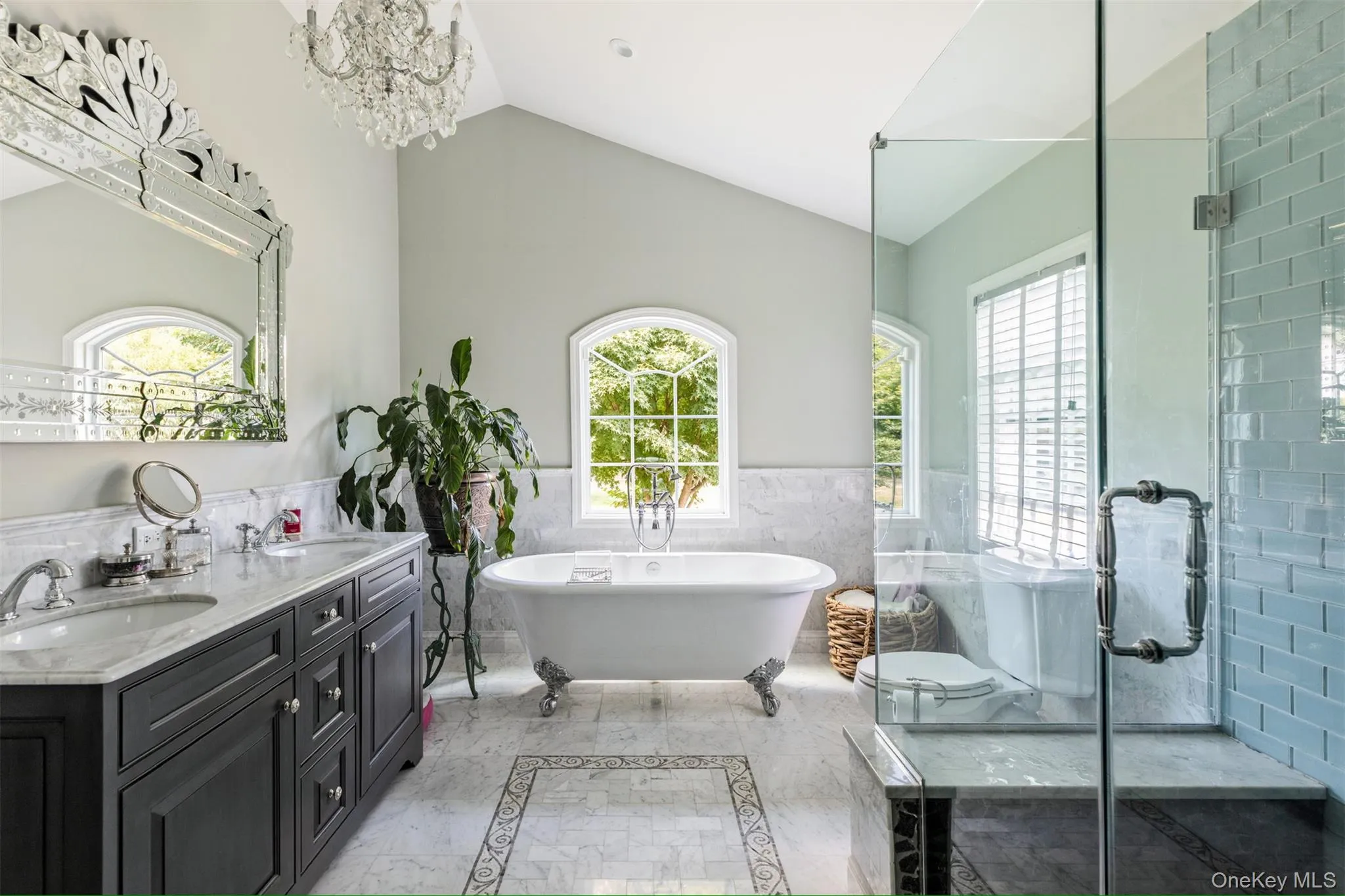 Bathroom featuring tile walls, a wainscoted wall, a freestanding bath, double vanity, and vaulted ceiling Bathroom featuring tile walls, a wainscoted wall, a freestanding bath, double vanity, and vaulted ceiling