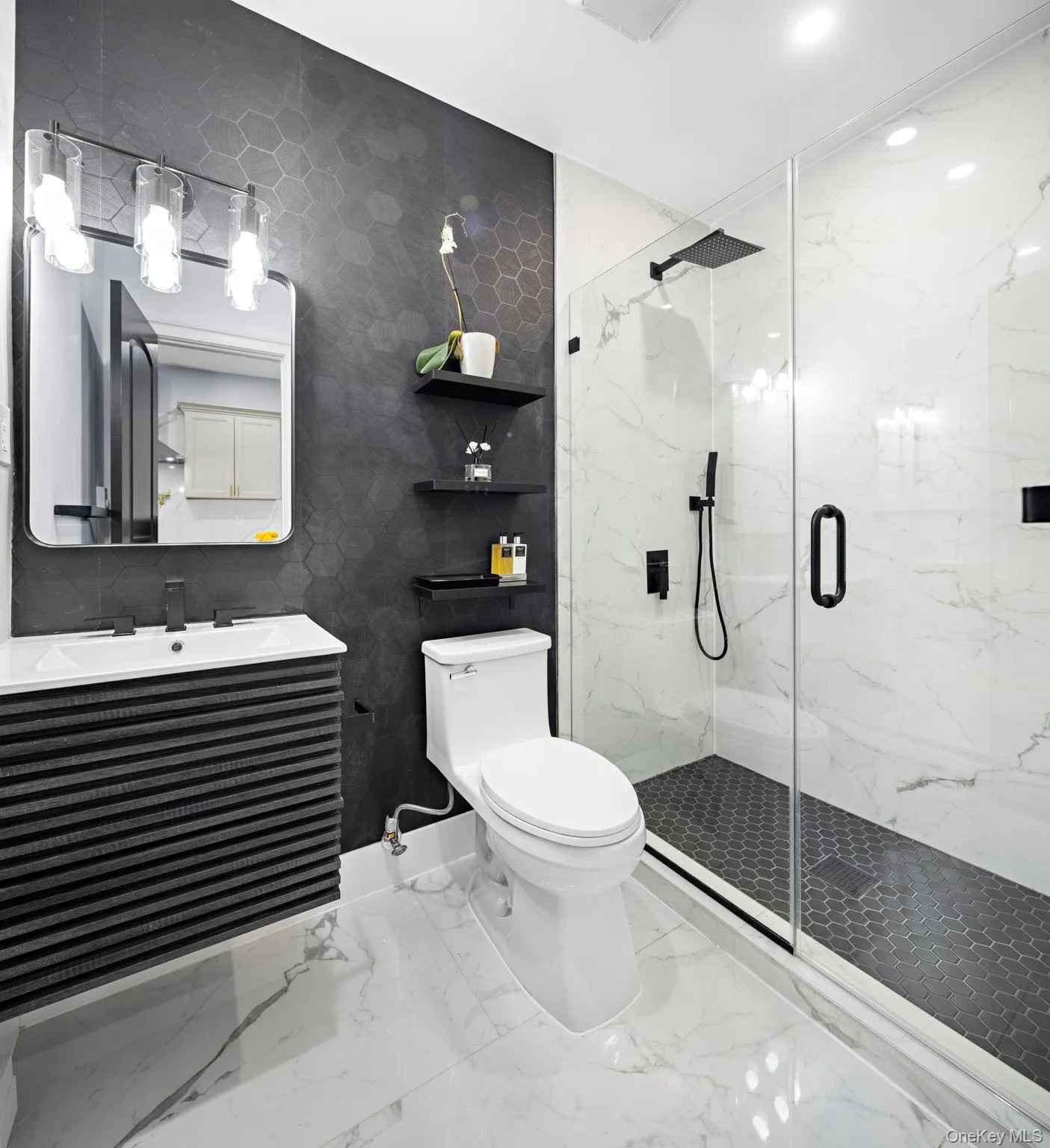 Bathroom featuring a marble finish shower, vanity, tile walls, and marble finish floors Bathroom featuring a marble finish shower, vanity, tile walls, and marble finish floors