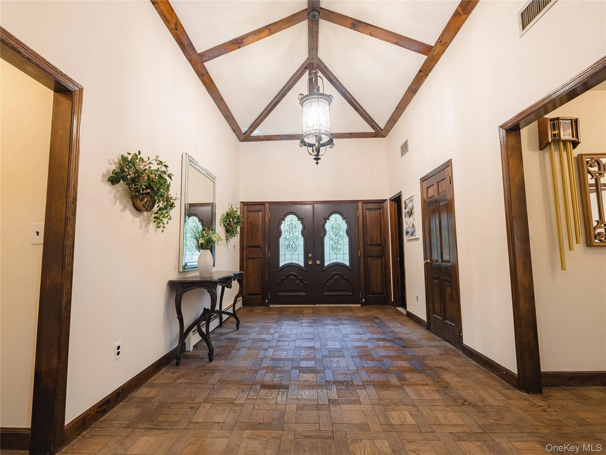 Entryway with high vaulted ceiling, a chandelier, and beam ceiling Entryway with high vaulted ceiling, a chandelier, and beam ceiling