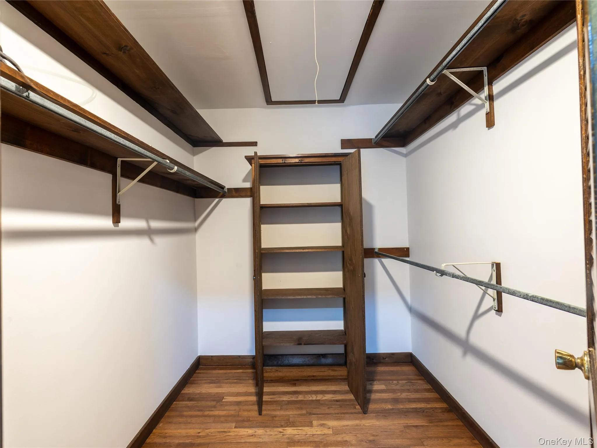 Walk in closet with attic access and dark wood-type flooring Walk in closet with attic access and dark wood-type flooring