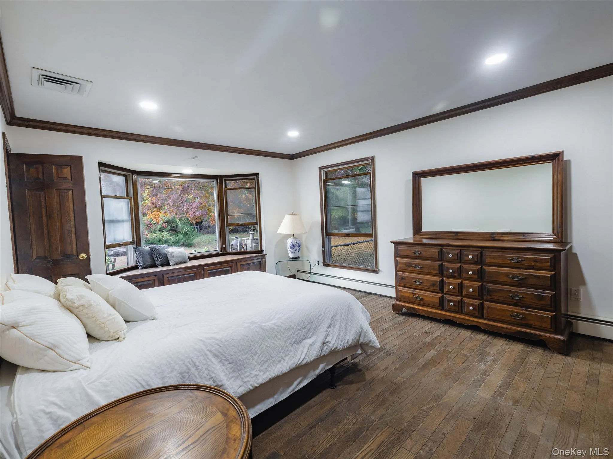 Bedroom featuring crown molding, a baseboard heating unit, dark wood-style flooring, and recessed lighting Bedroom featuring crown molding, a baseboard heating unit, dark wood-style flooring, and recessed lighting