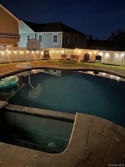 Pool at twilight with a fenced backyard and a patio Pool at twilight with a fenced backyard and a patio