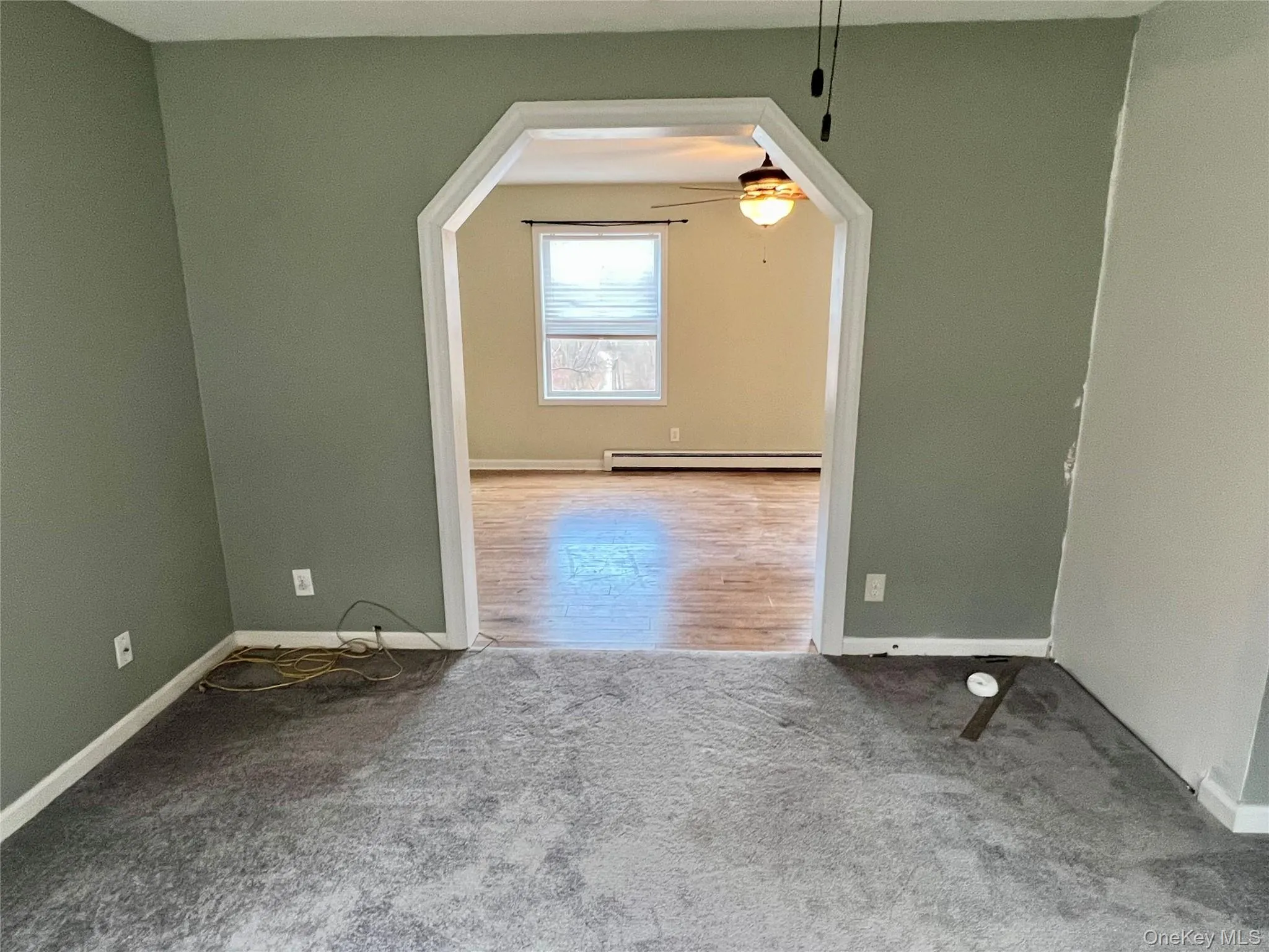 Carpeted spare room featuring ceiling fan, arched walkways, and baseboard heating Carpeted spare room featuring ceiling fan, arched walkways, and baseboard heating