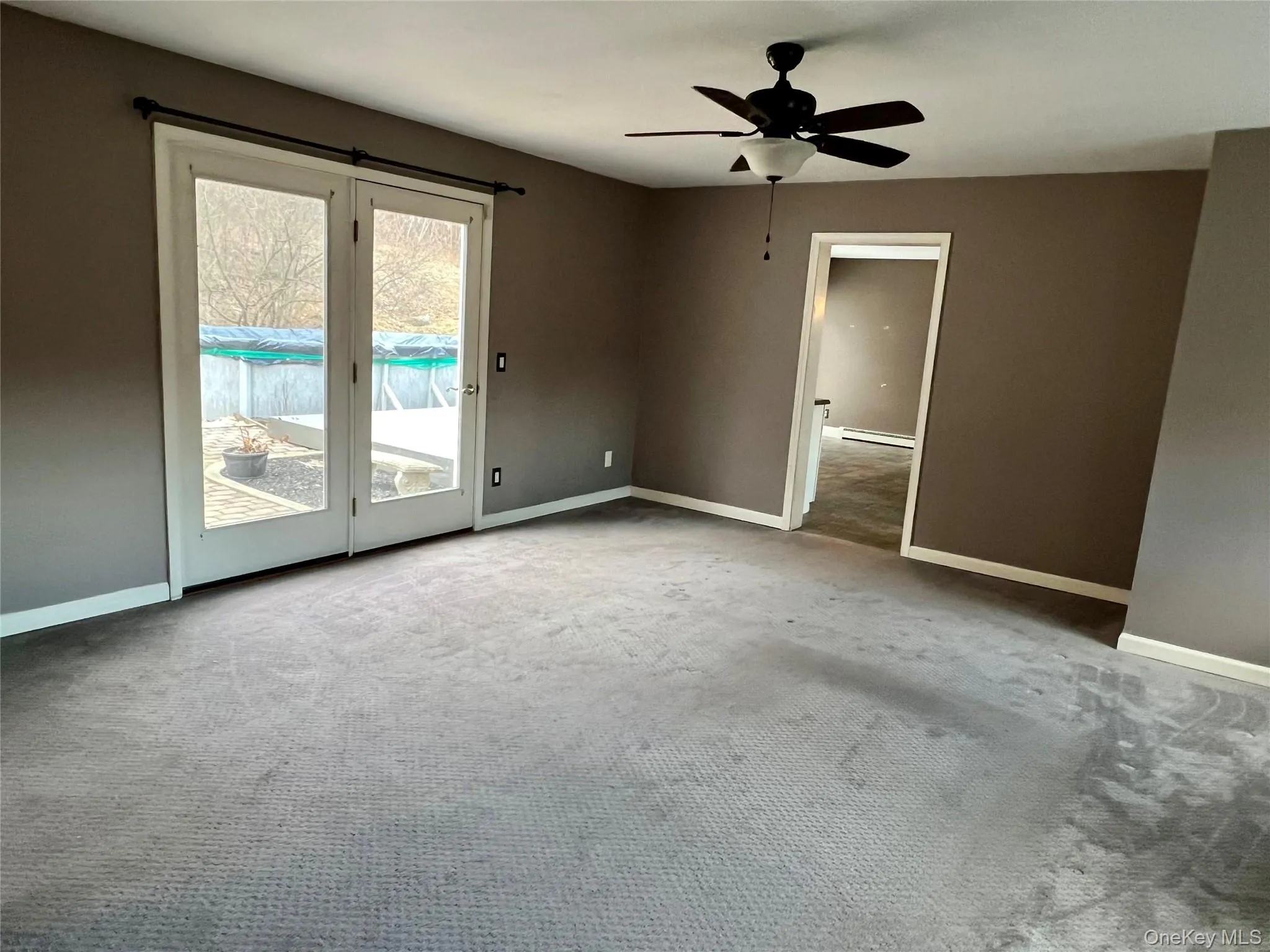 Unfurnished room featuring light carpet, a ceiling fan, and baseboard heating Unfurnished room featuring light carpet, a ceiling fan, and baseboard heating