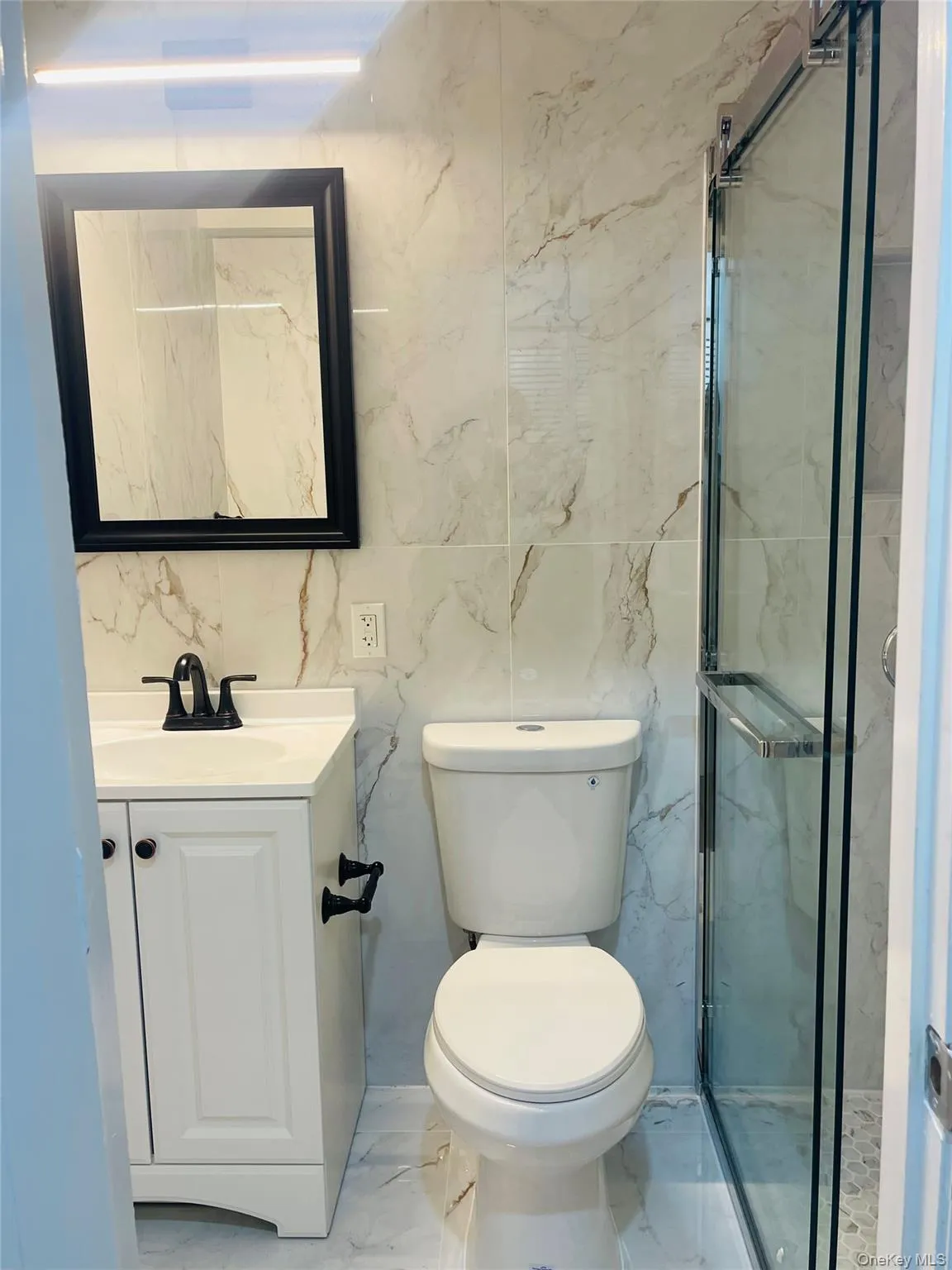 Full bath featuring vanity, light marble finish flooring, and a stall shower Full bath featuring vanity, light marble finish flooring, and a stall shower