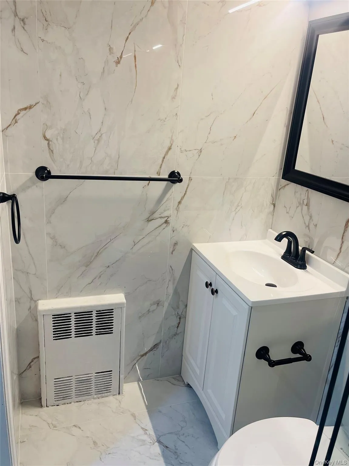 Bathroom with vanity, light marble finish flooring, heating unit, tile walls, and stone wall Bathroom with vanity, light marble finish flooring, heating unit, tile walls, and stone wall