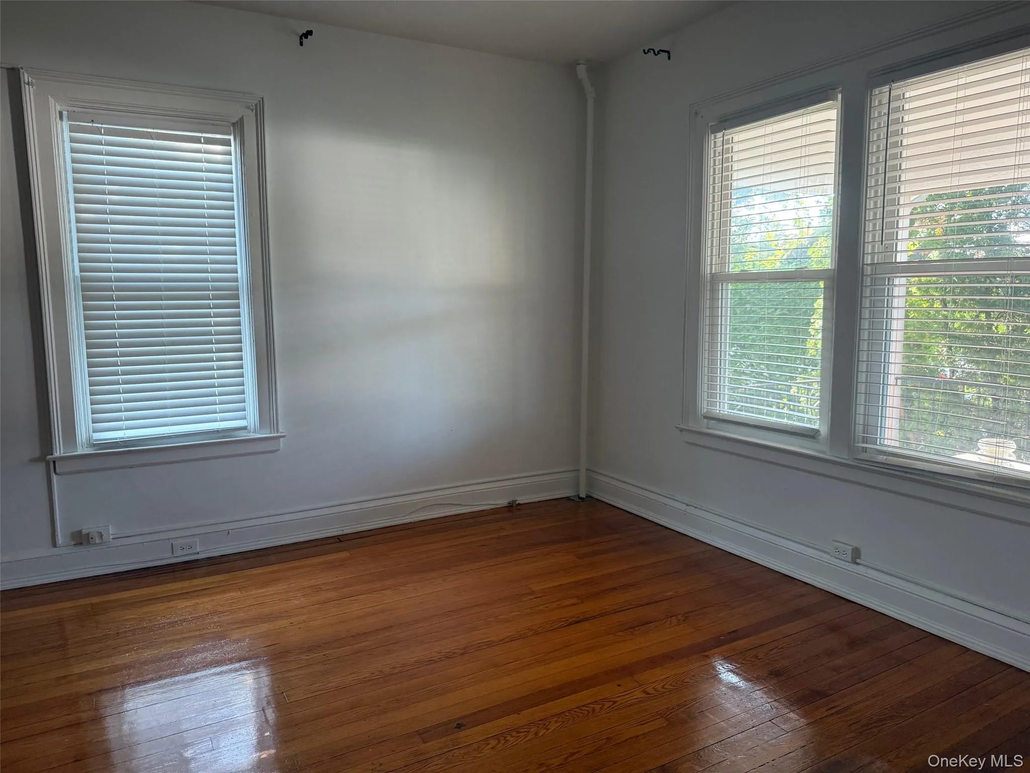 Unfurnished room with dark wood-style floors and baseboards Unfurnished room with dark wood-style floors and baseboards