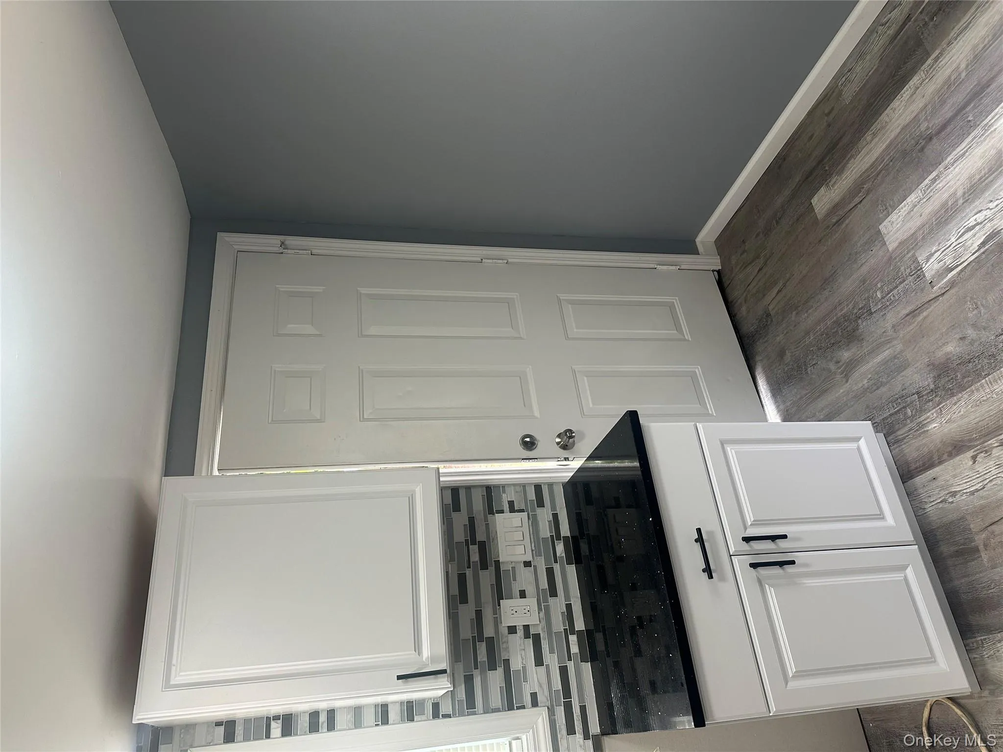 Kitchen with white cabinetry, tasteful backsplash, light wood finished floors, and dark stone counters Kitchen with white cabinetry, tasteful backsplash, light wood finished floors, and dark stone counters