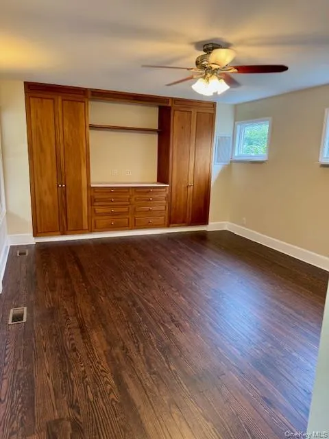 featuring dark wood finished floors and ceiling fan and built ins featuring dark wood finished floors and ceiling fan and built ins