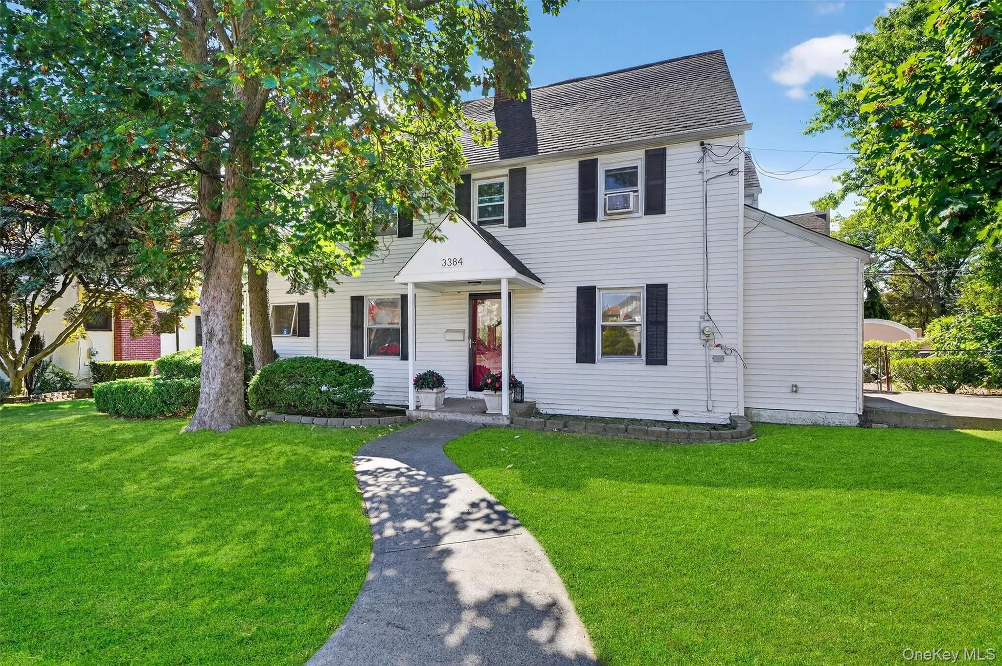 Colonial-style house featuring roof with shingles and a front yard Colonial-style house featuring roof with shingles and a front yard