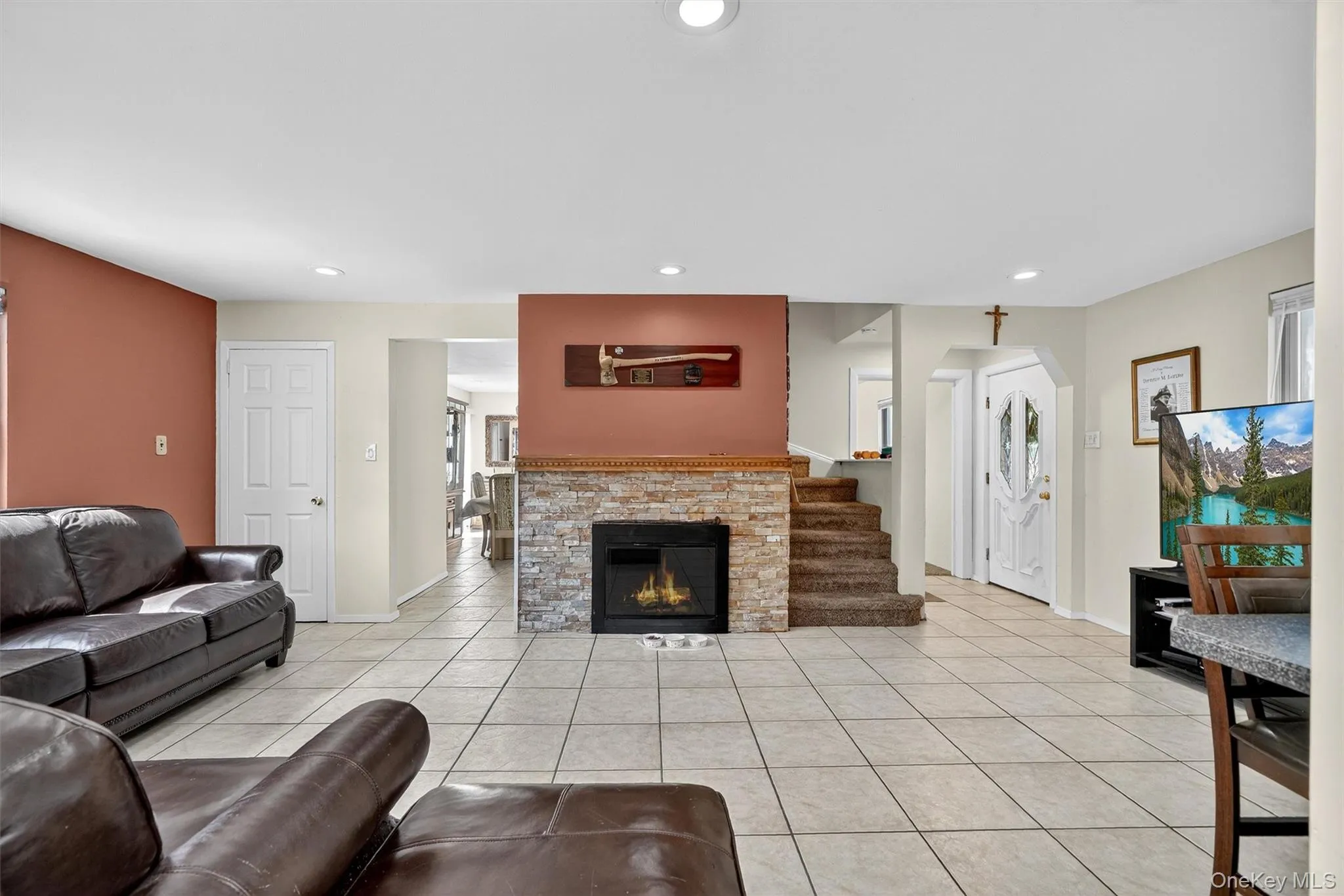 Living room with light tile patterned flooring, recessed lighting, a fireplace, and arched walkways Living room with light tile patterned flooring, recessed lighting, a fireplace, and arched walkways