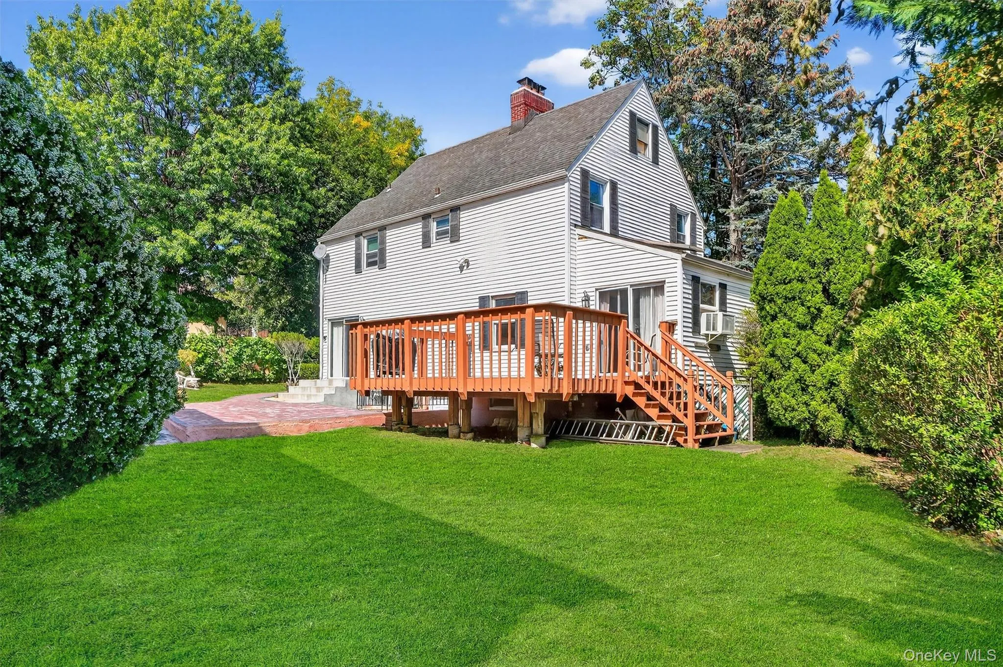 Back of property featuring a yard, a chimney, roof with shingles, and a wooden deck Back of property featuring a yard, a chimney, roof with shingles, and a wooden deck
