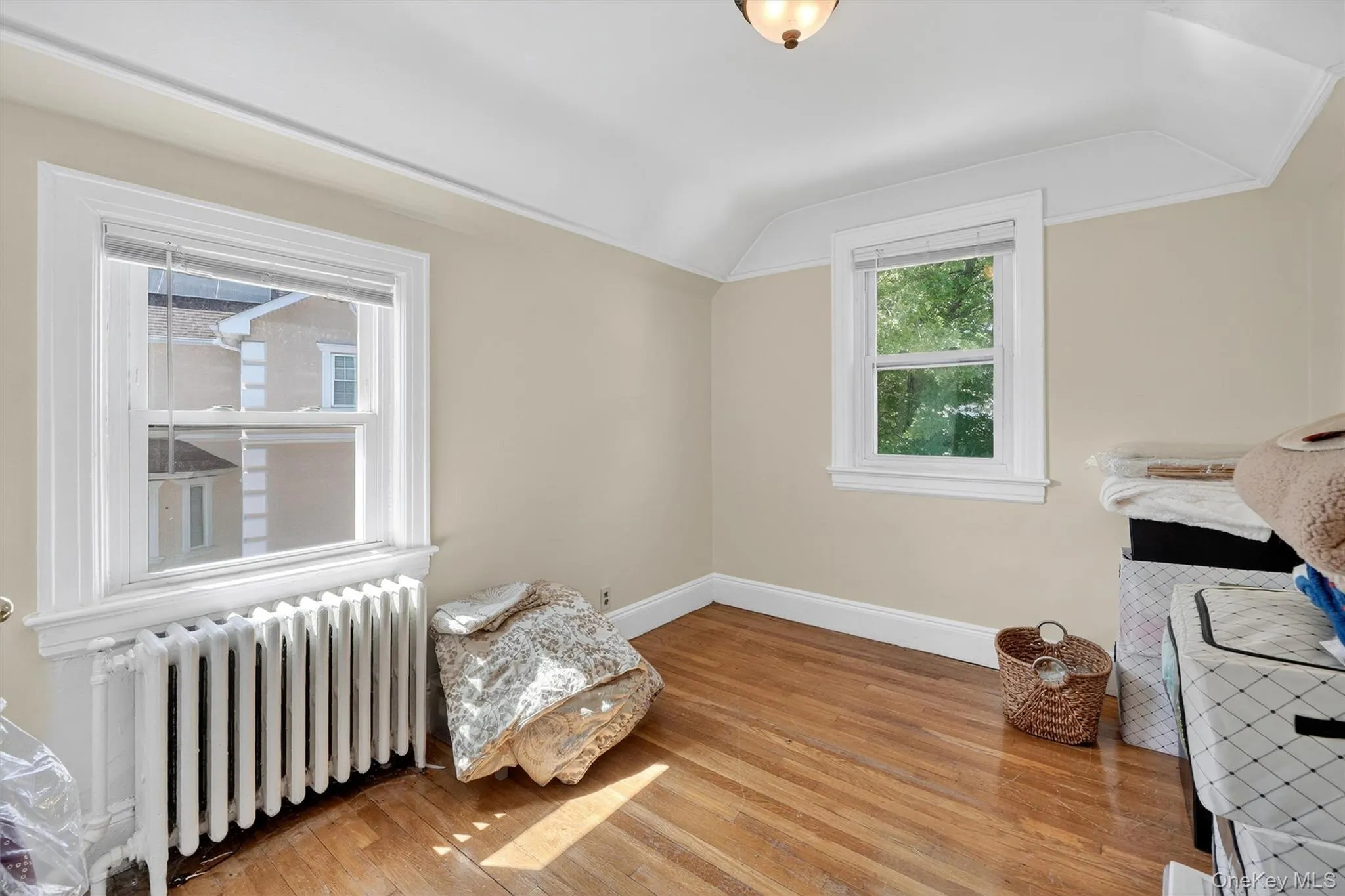 Bedroom with radiator heating unit, light wood-style flooring, and lofted ceiling Bedroom with radiator heating unit, light wood-style flooring, and lofted ceiling