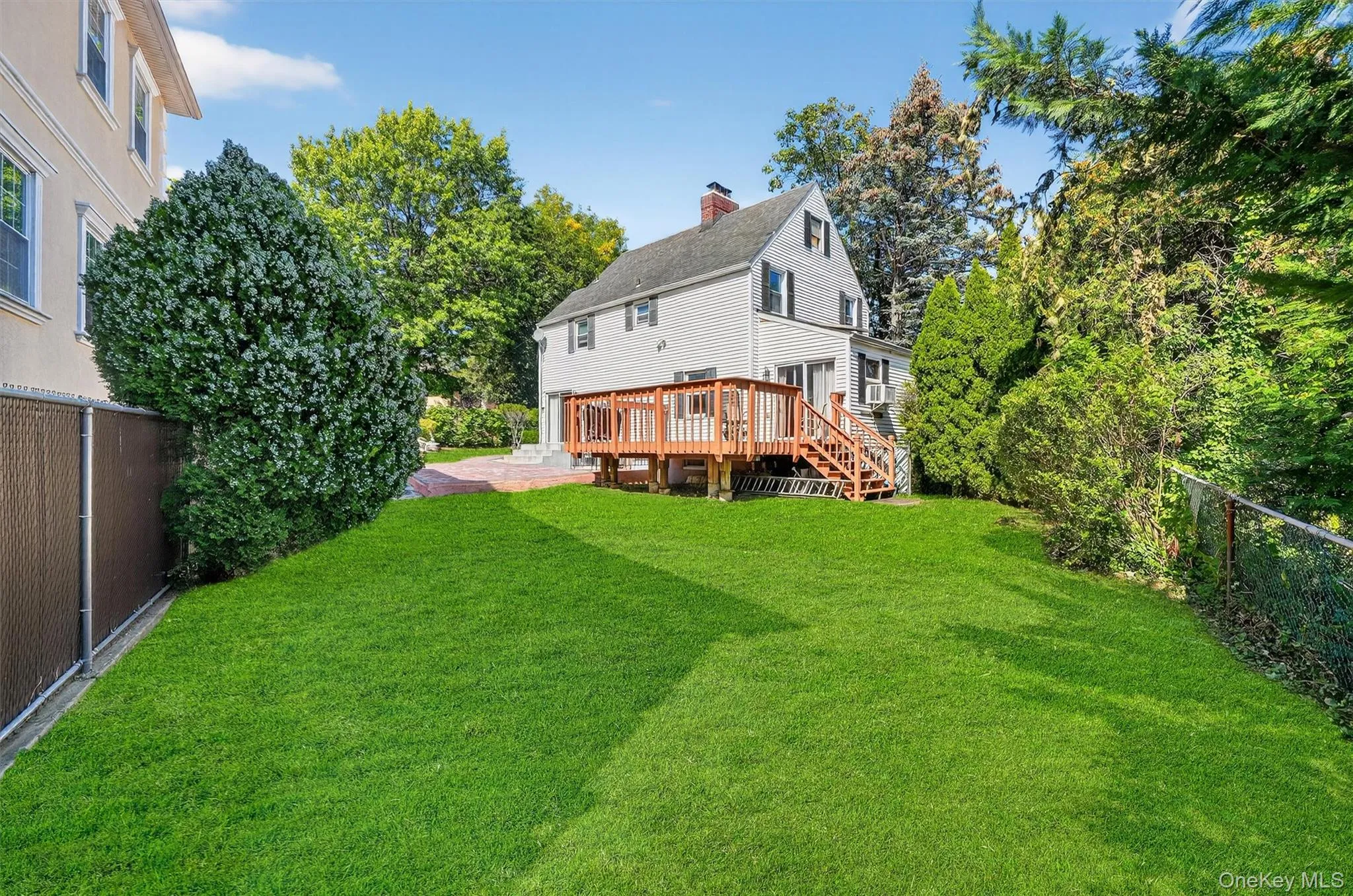 Back of house featuring a fenced backyard, a chimney, a deck, and stairway Back of house featuring a fenced backyard, a chimney, a deck, and stairway