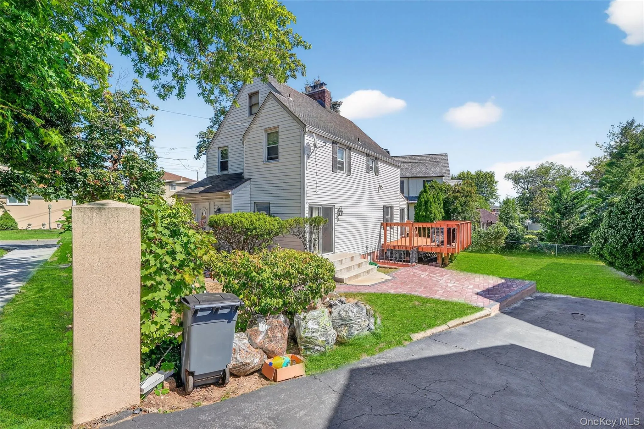 View of side of property featuring a wooden deck, a chimney, a patio, and a shingled roof View of side of property featuring a wooden deck, a chimney, a patio, and a shingled roof